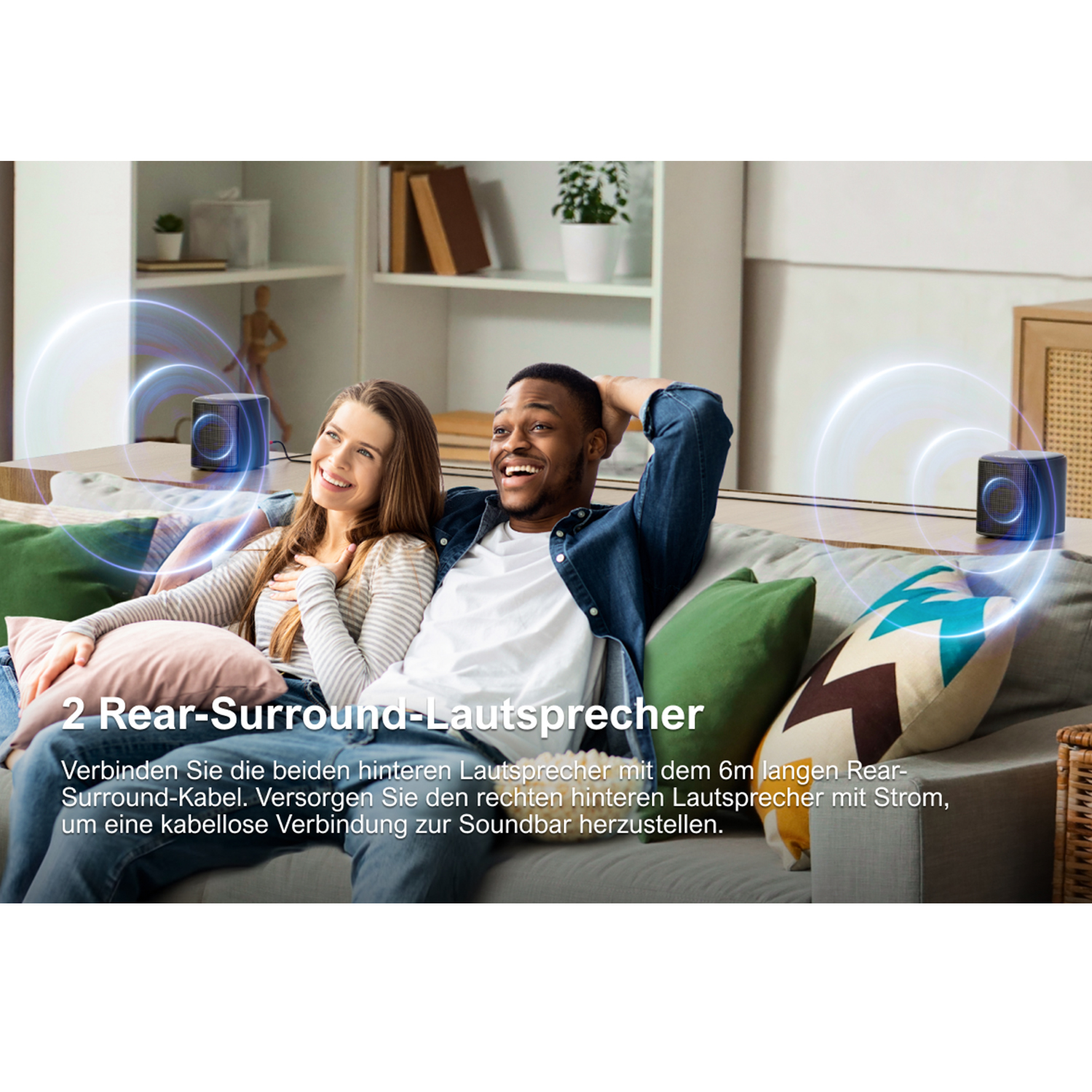 Ein Paar sitzt auf einem Sofa mit zwei Lautsprechern hinter sich. Text: 2 Rear-Surround-Lautsprecher.
