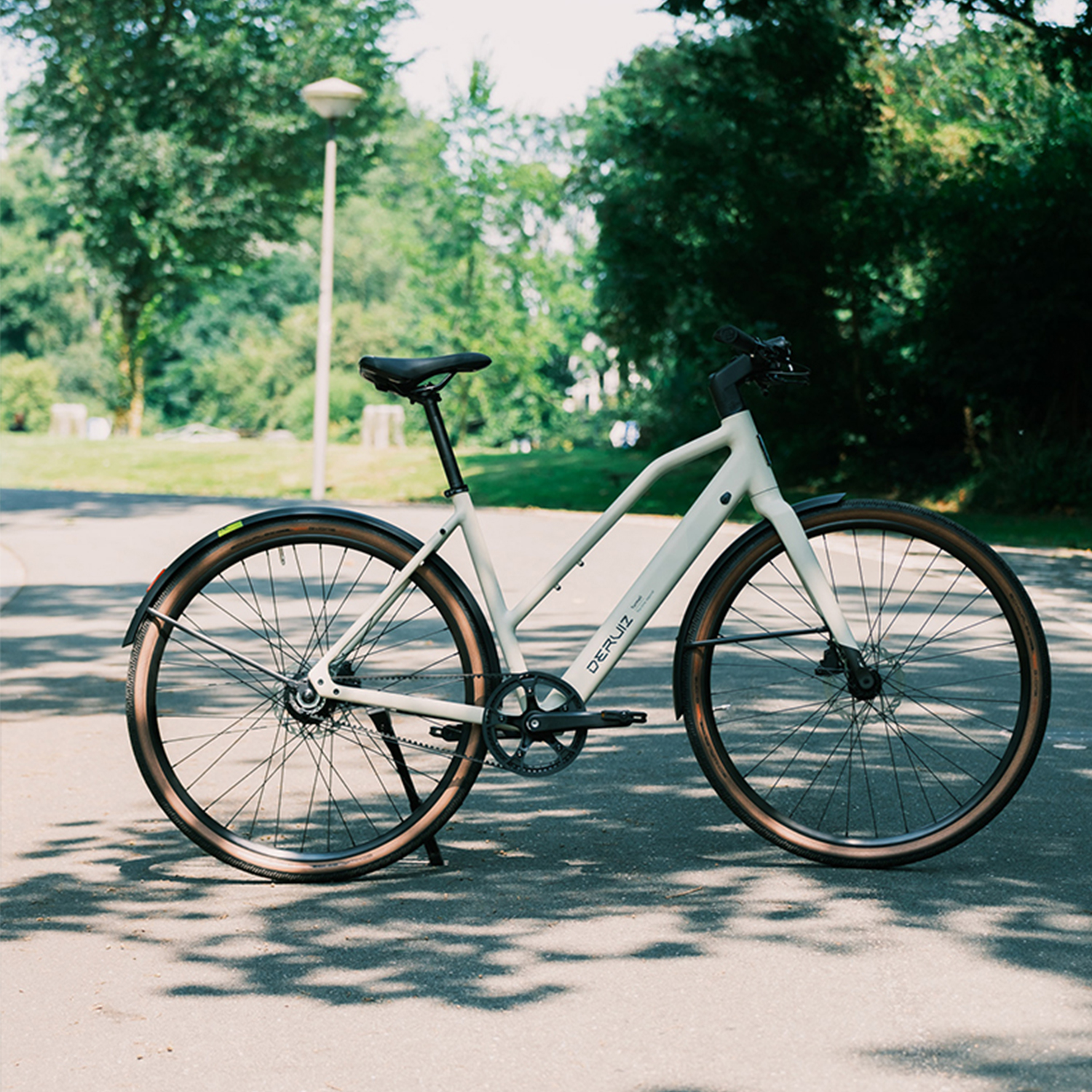 Ein hellgraues Citybike. Es hat schwarze Reifen, Schutzbleche, einen schwarzen Sattel und einen schwarzen Lenker.