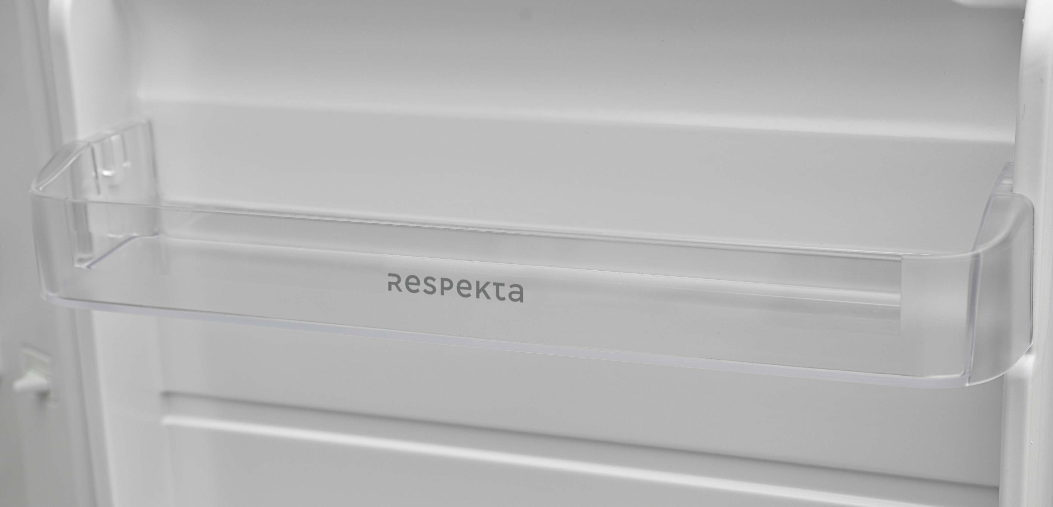 A clear plastic shelf inside a white refrigerator, labeled with the word Respekta.