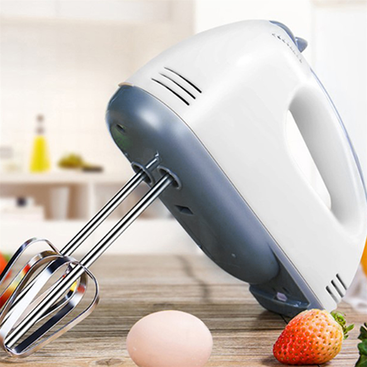 Weißer und grauer Handmixer auf Holztisch. Erdbeere und Ei liegen auf dem Tisch.