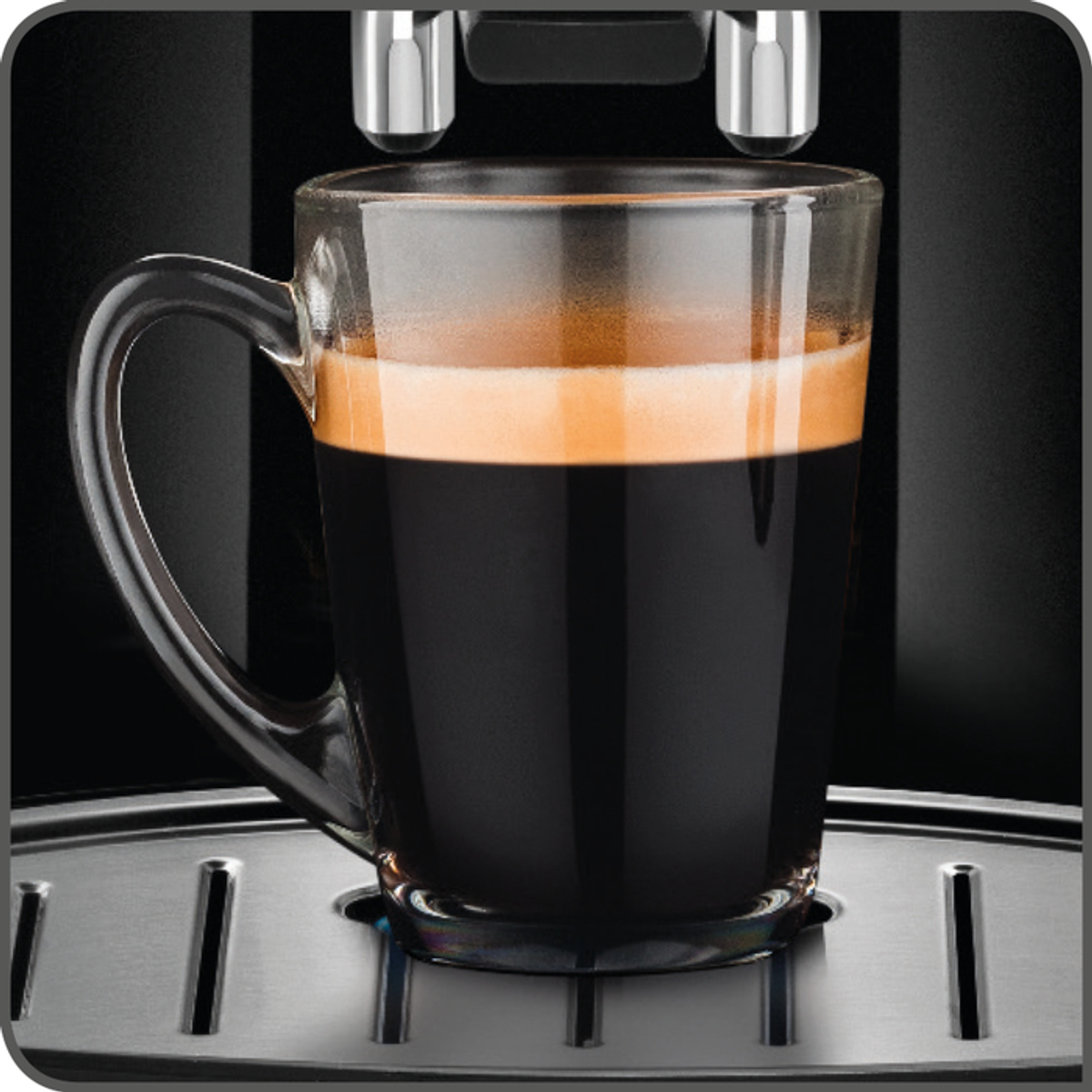 Una tazza di vetro trasparente di caffè scuro si trova su un vassoio d'argento. La tazza ha un manico.