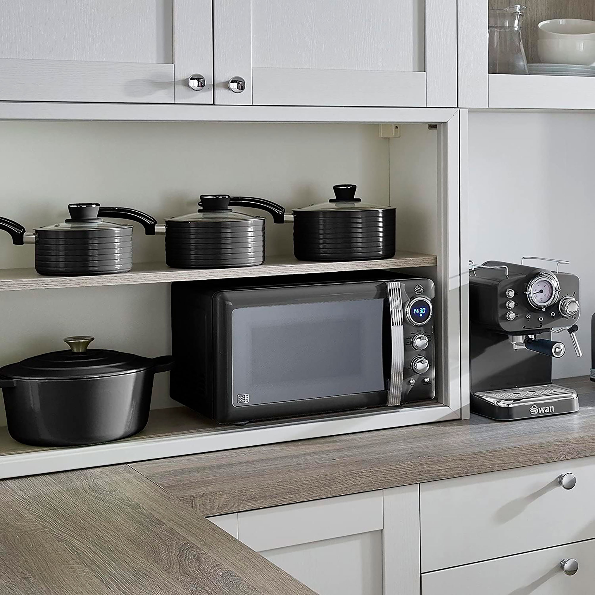Una escena de cocina con microondas, sartenes y una máquina de espresso.
