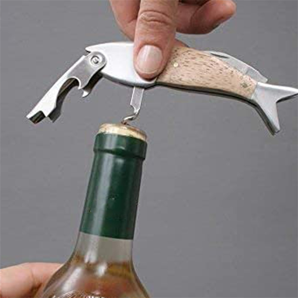 Fischförmiger Flaschenöffner öffnet eine Flasche. Holzgriff, Metallkopf. Grüne Flasche.