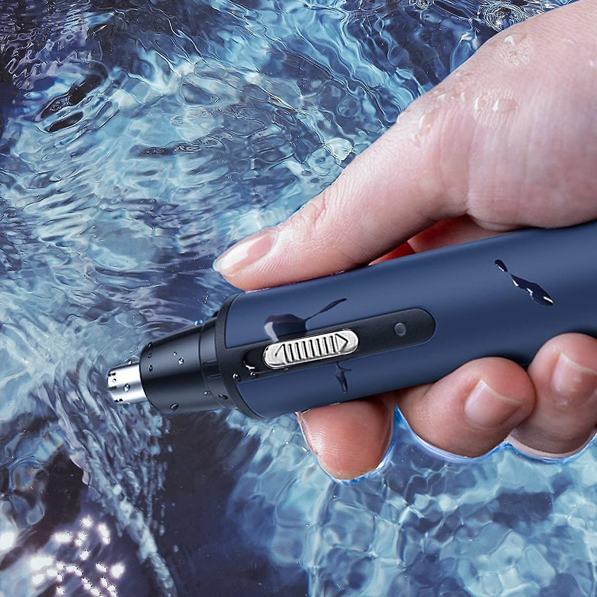 Eine Hand hält einen blau-silbernen Nasenhaartrimmer über Wasser. Der Trimmer hat eine silberne Klinge.