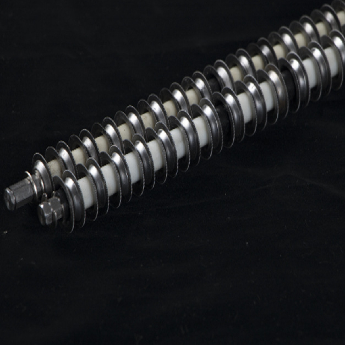Zwei metallische Schneckenschrauben mit weißen und silbernen Elementen auf schwarzem Untergrund.