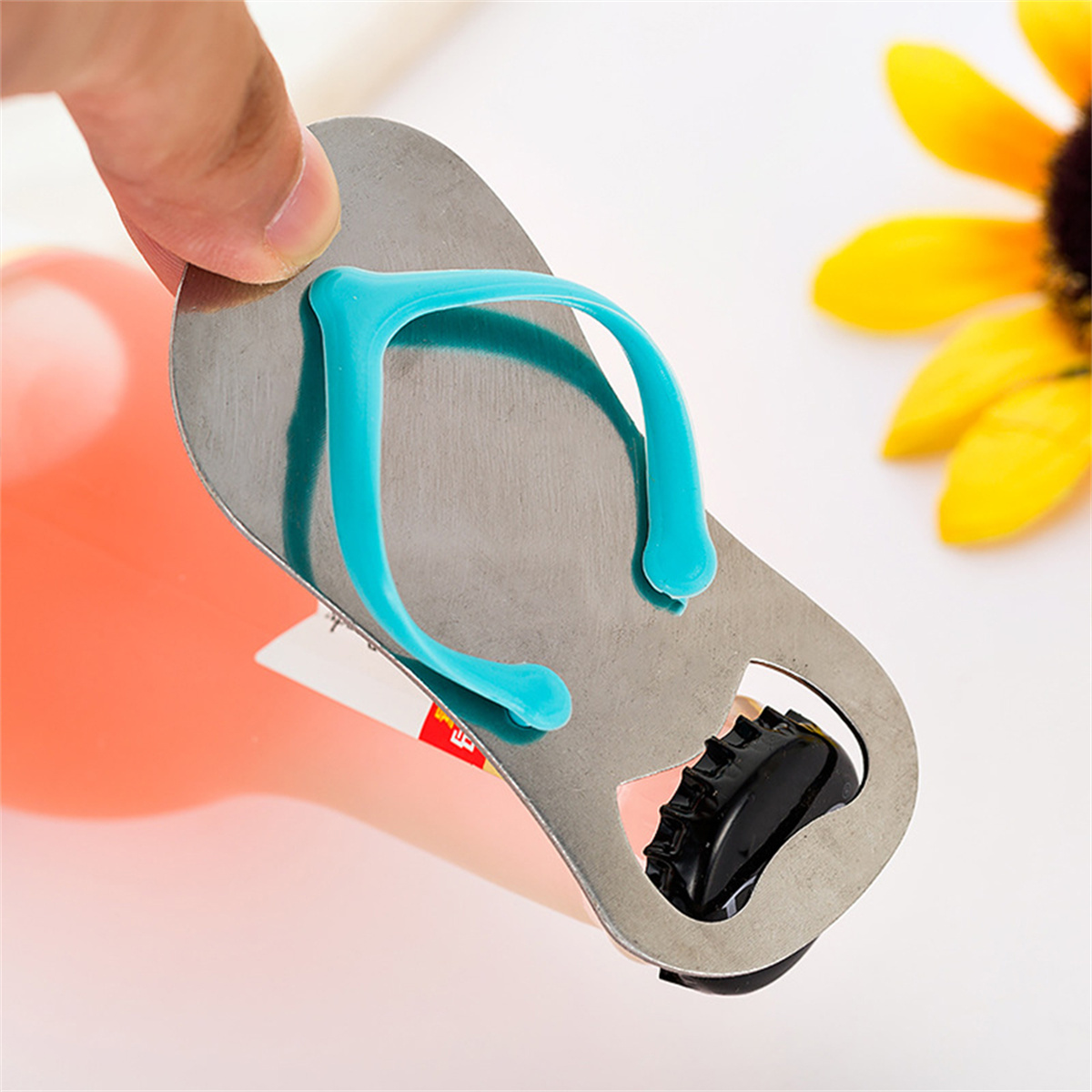 Ein silberner Flaschenöffner in Form eines Flip-Flops, der eine Flasche mit rosa Flüssigkeit öffnet.