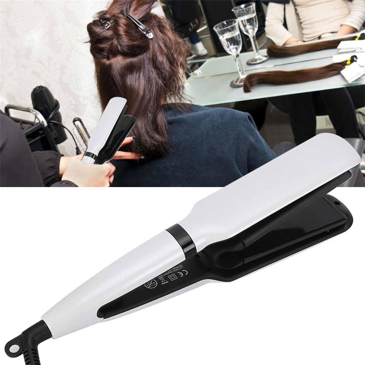 Friseur hält ein Glätteisen. Der Kunde sitzt vor einem Spiegel. Haarverlängerungen sind sichtbar.