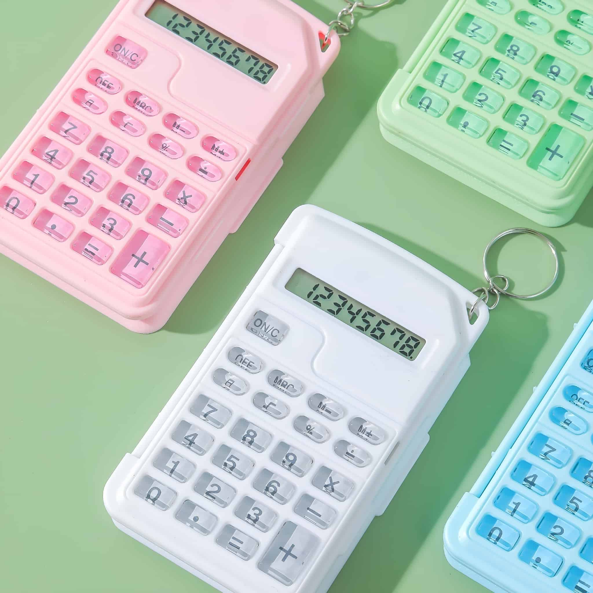 Vier kleine Taschenrechner in Rosa, Weiß, Grün und Blau. Sie haben Tasten und Displays mit Zahlen.
