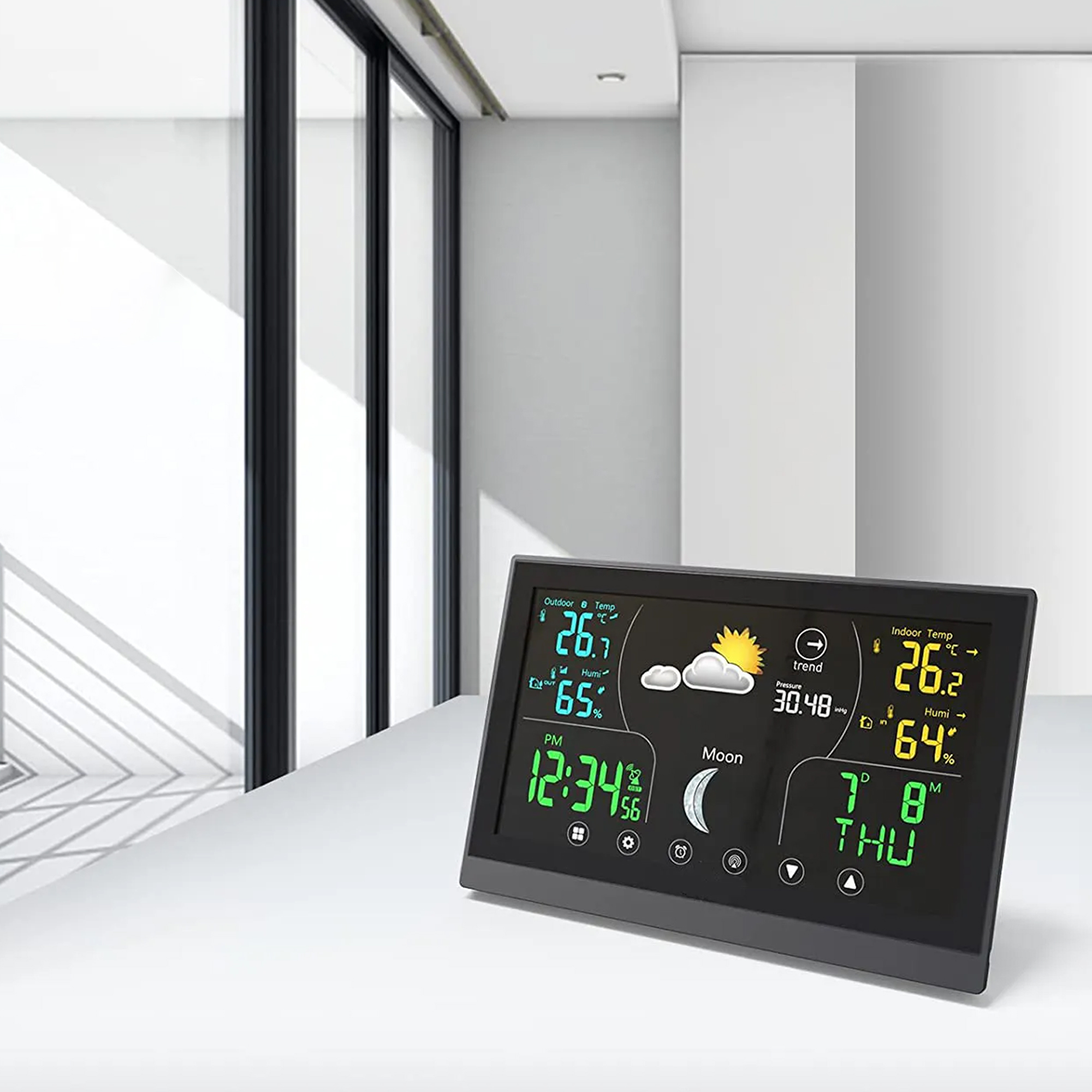 A black digital weather station displaying temperature, humidity, time, and moon phase.