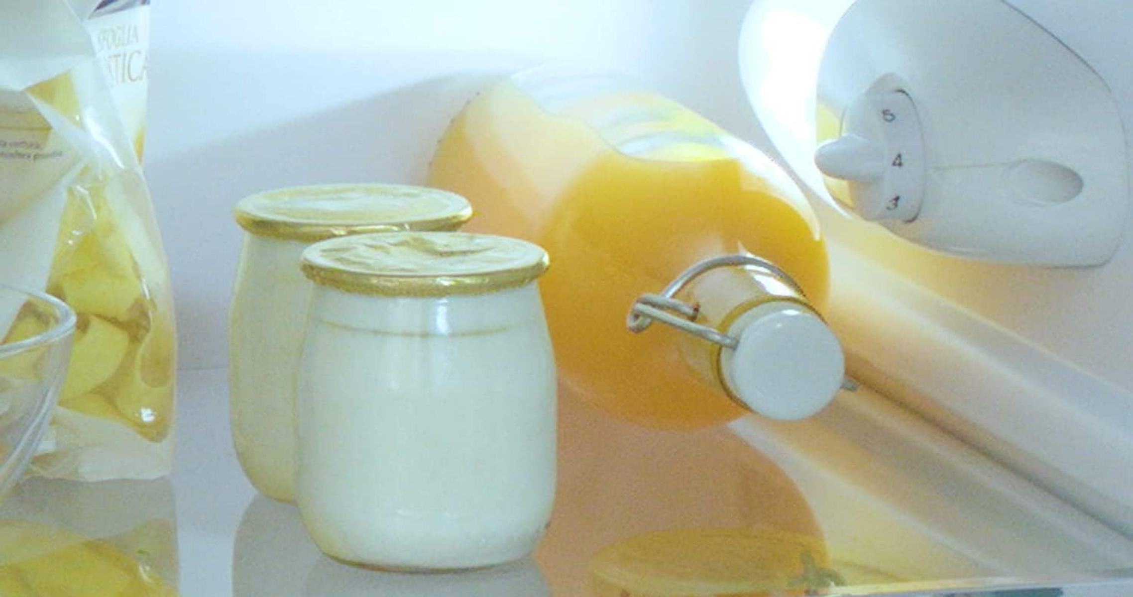 Im Kühlschrank sind Joghurtgläser und eine Flasche Orangensaft zu sehen.
