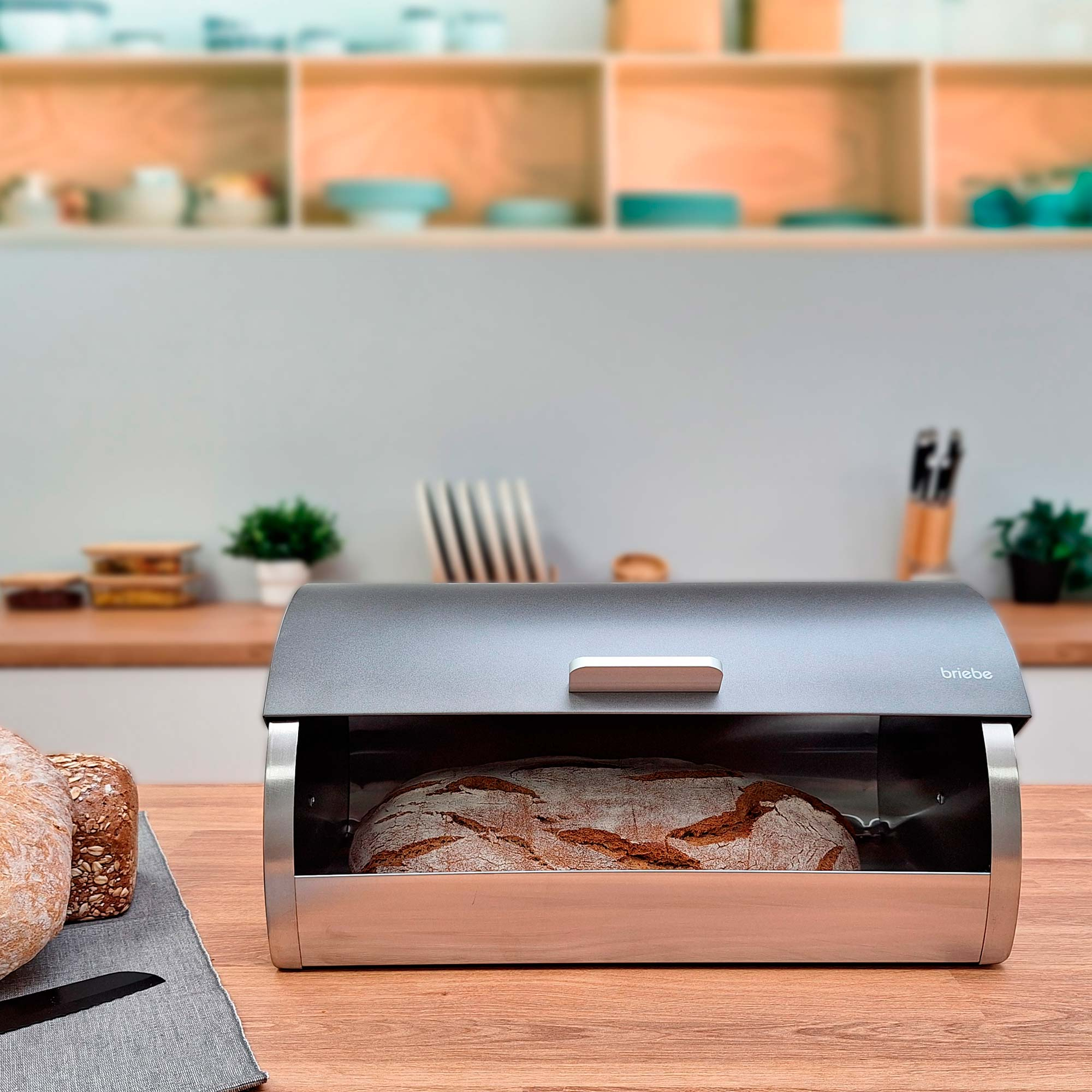 Una panera con pan dentro, sobre una superficie de madera con fondo de cocina.