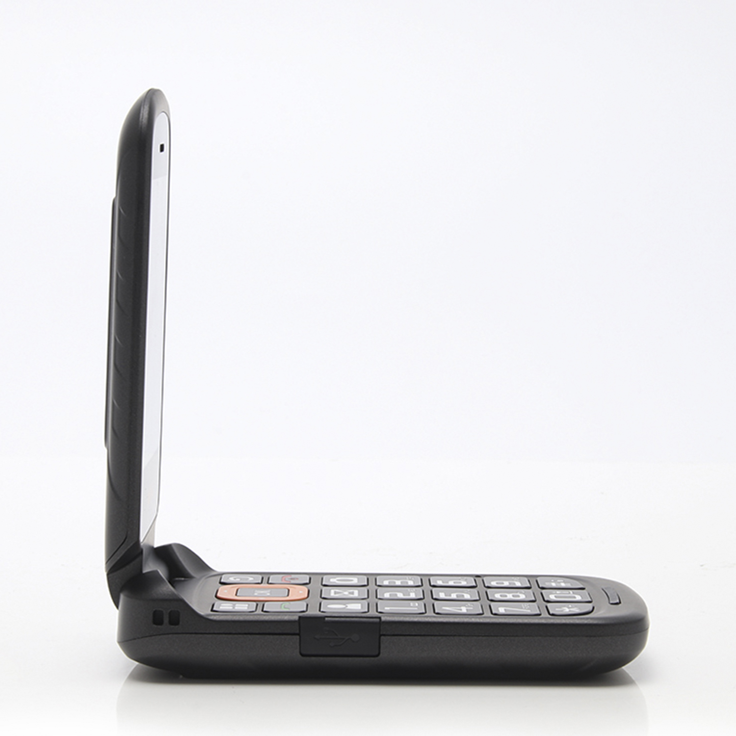 Un teléfono plegable negro, visto de lado. El teléfono está abierto. Está sobre una superficie blanca.