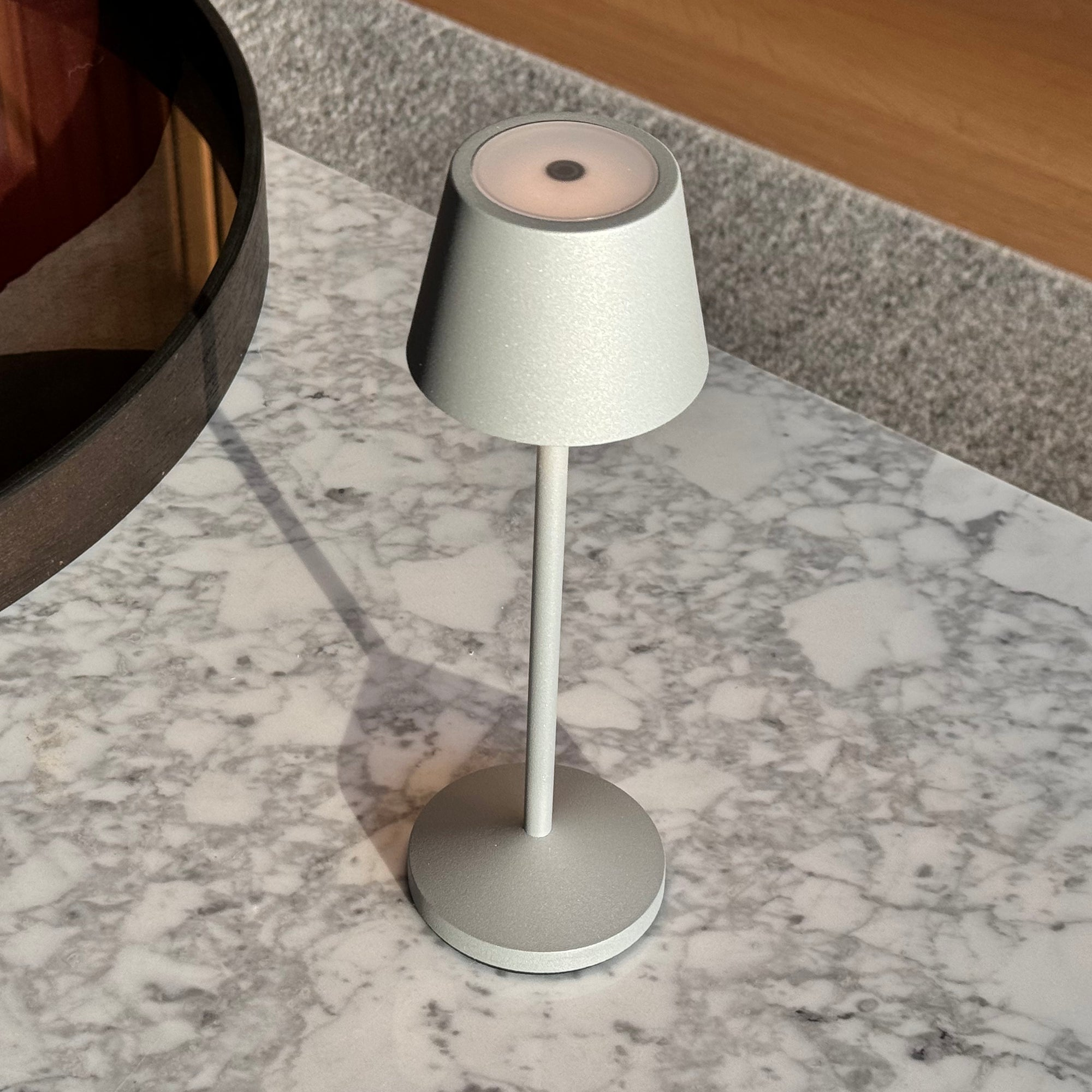 Eine kleine silberne Lampe steht auf einem weißen Marmortisch.