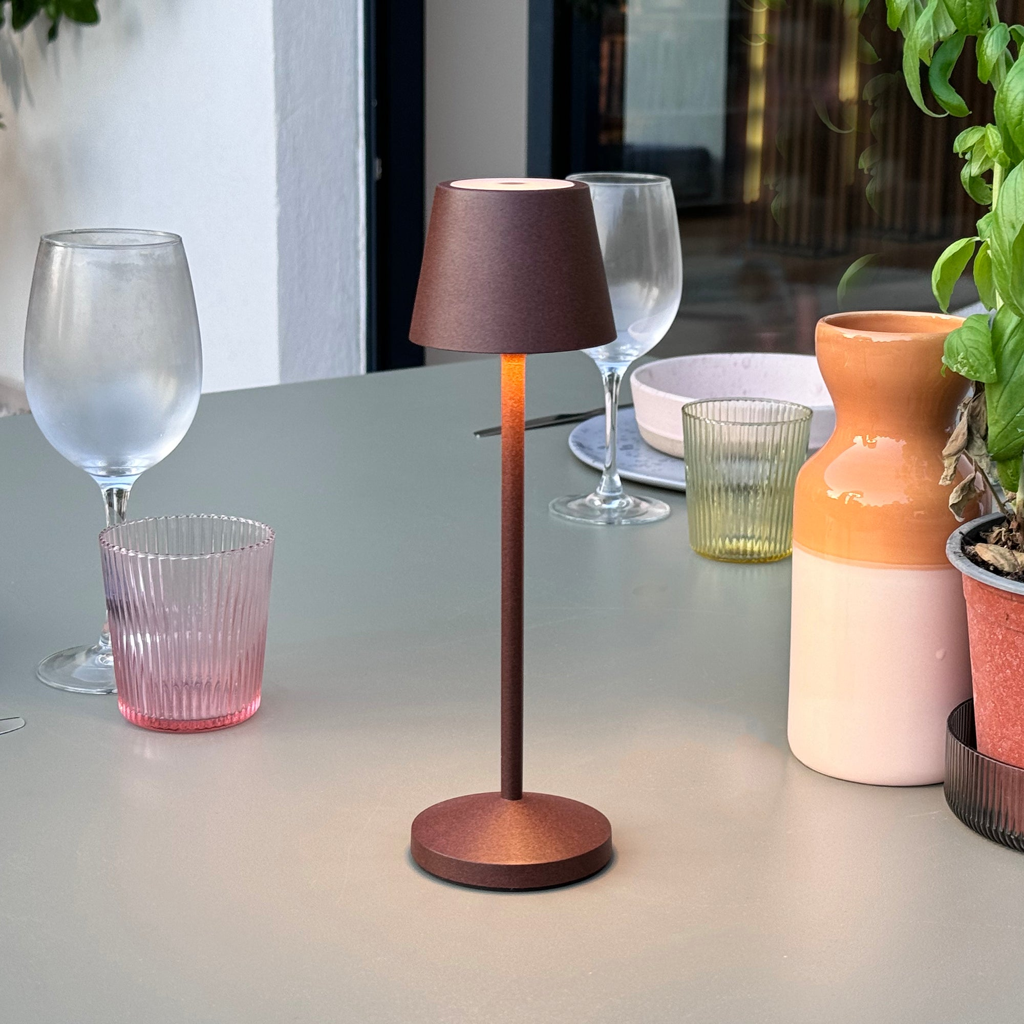 Eine Tischlampe mit braunem Schirm, Stiel und Fuß steht auf einem grünen Tisch.