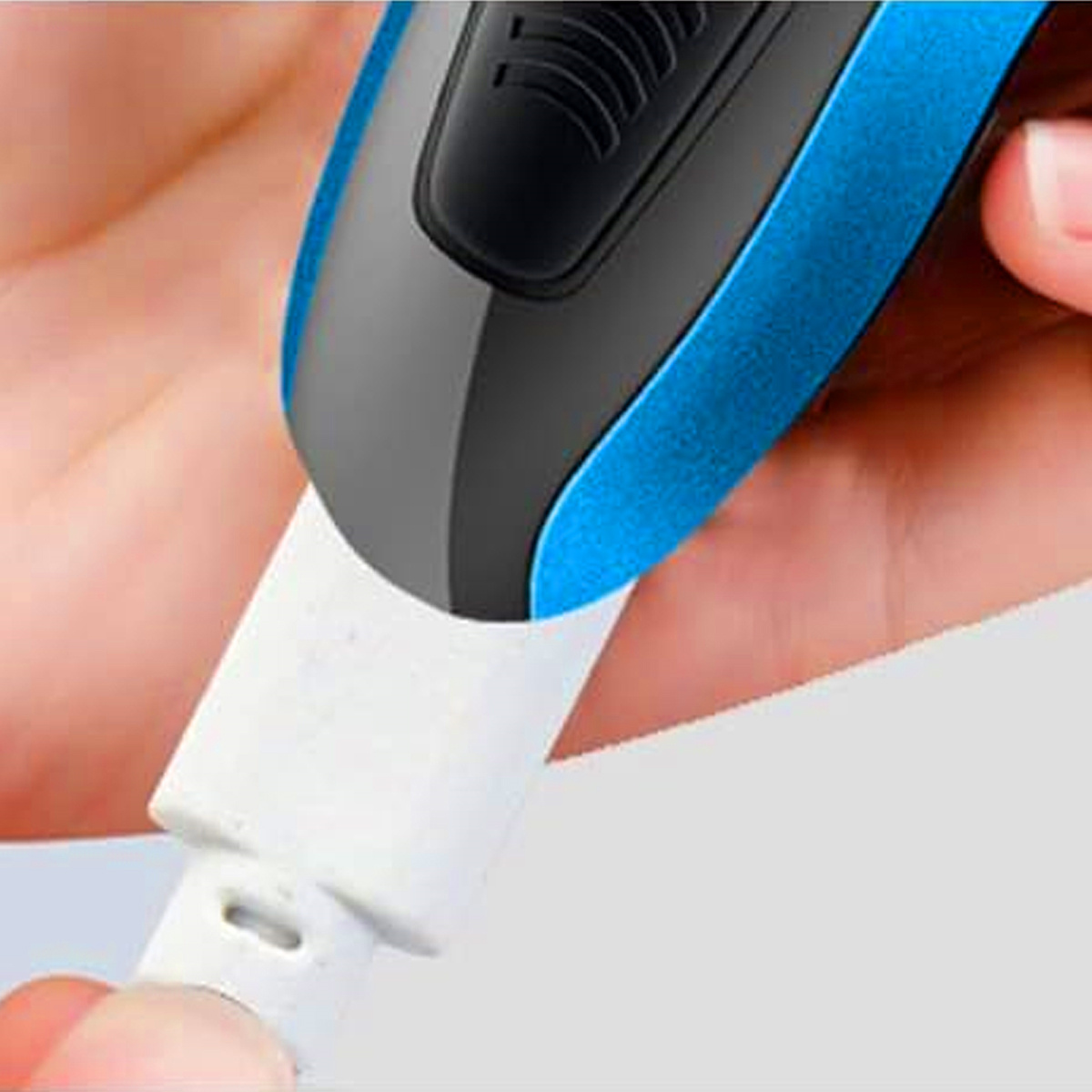 Hand verbindet weißen USB-Stecker mit blau-schwarzem Gerät. Nahaufnahme. Weißer Hintergrund.