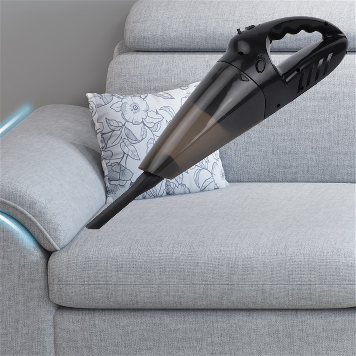 Schwarzer Handstaubsauger über einem grauen Sofa mit Kissen. Eine hellblaue Linie ist sichtbar.