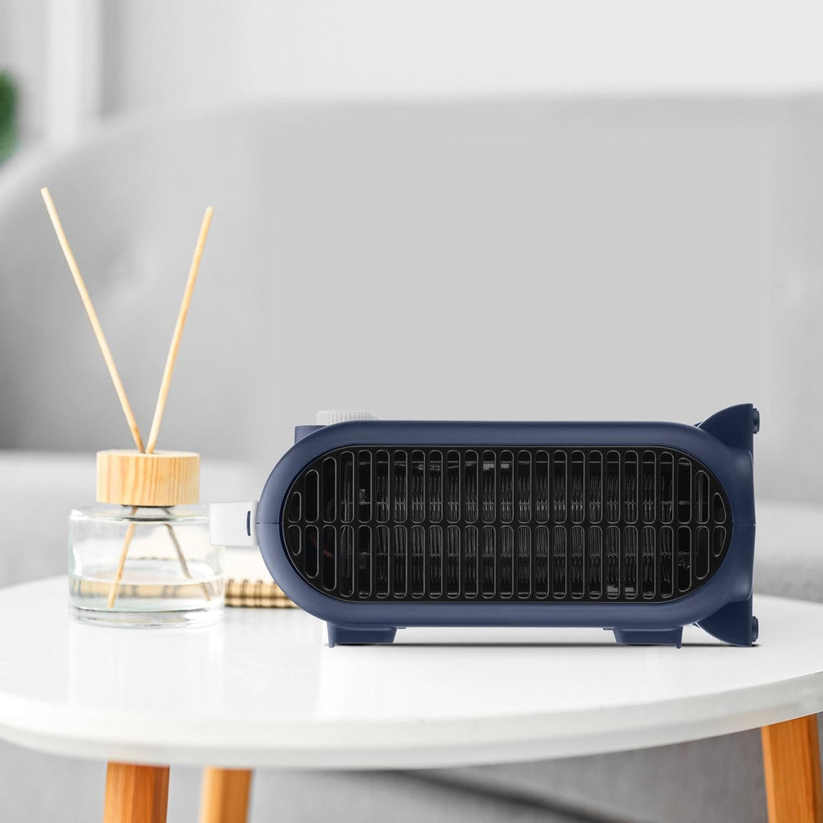 Niebieski, owalny grzejnik elektryczny z dyfuzorem powietrza i stołem.