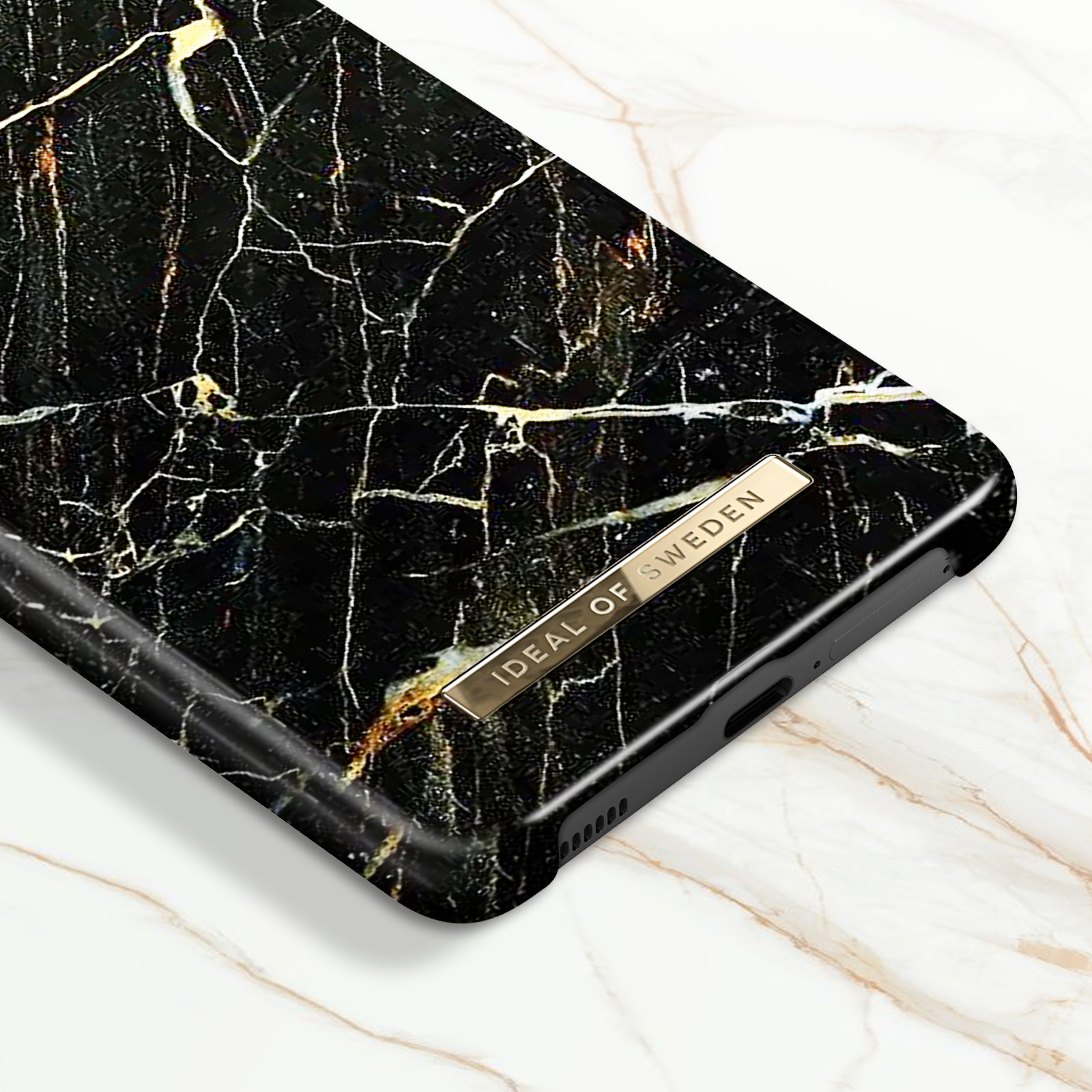 Primo piano di una custodia per telefono con design a marmo, etichetta oro: IDEAL.
