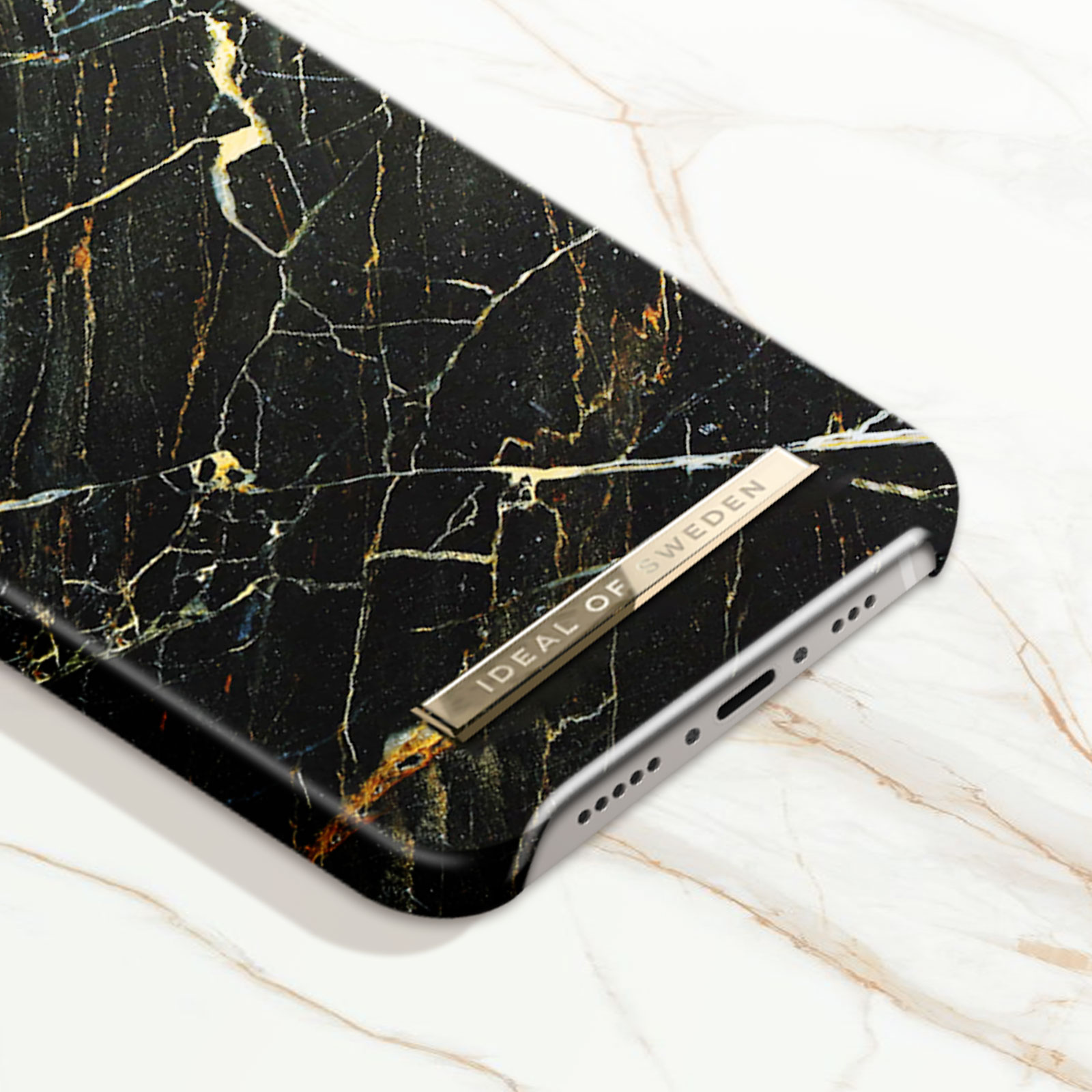 Custodia nera per telefono con design marmorizzato e un'etichetta dorata Ideal of Sweden.