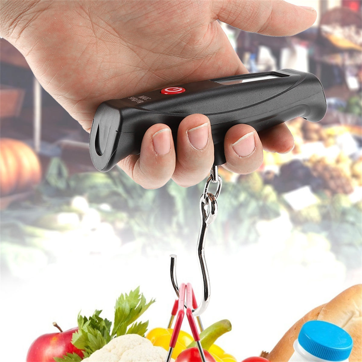 Hand hält eine schwarze Digitalwaage mit Haken. Hintergrund ist ein Markt.