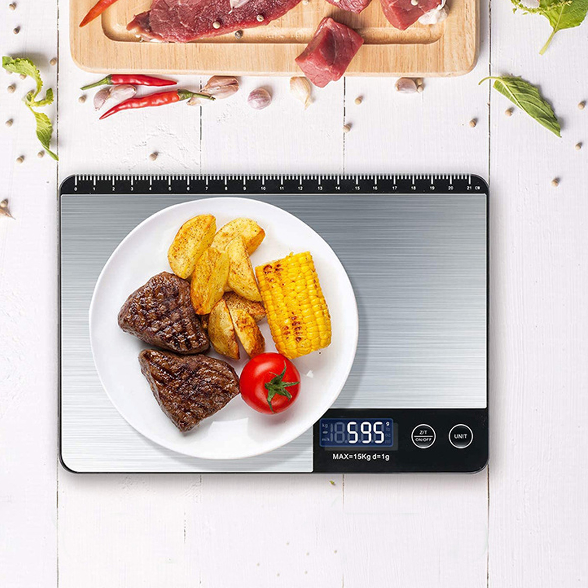 Eine Digitalwaage mit Essen, darunter Steak, Kartoffeln, Mais und eine Tomate, auf einem weißen Holztisch.