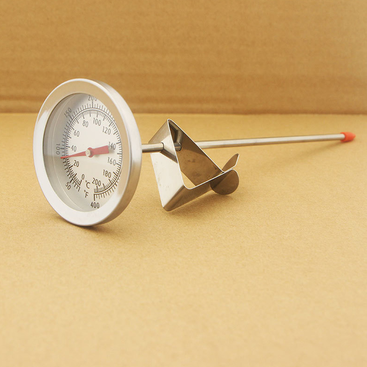 Ein Metallthermometer mit roter Spitze auf braunem Untergrund. Die Anzeige ist 140.