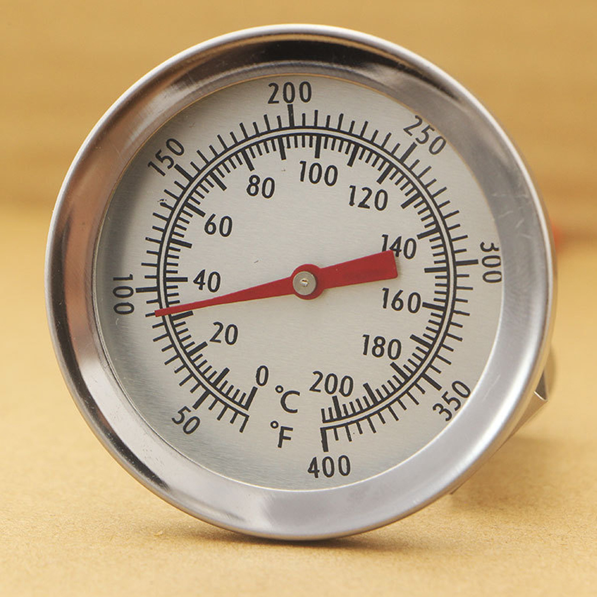 Ein silbernes, rundes Thermometer mit roter Nadel. Es zeigt eine Temperaturanzeige in Celsius und Fahrenheit.