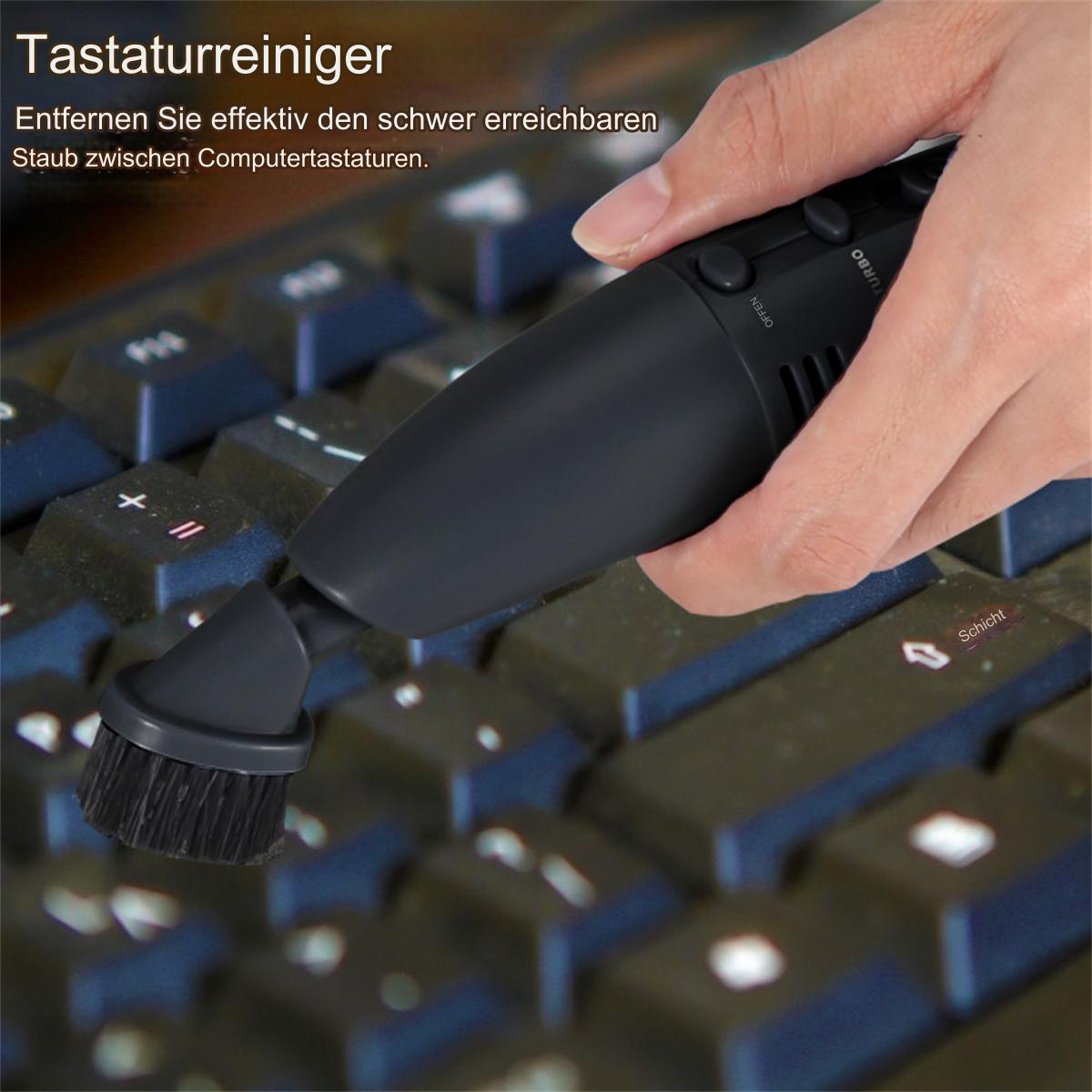 Eine Hand reinigt eine Tastatur mit einem schwarzen bürstenbesetzten Gerät.