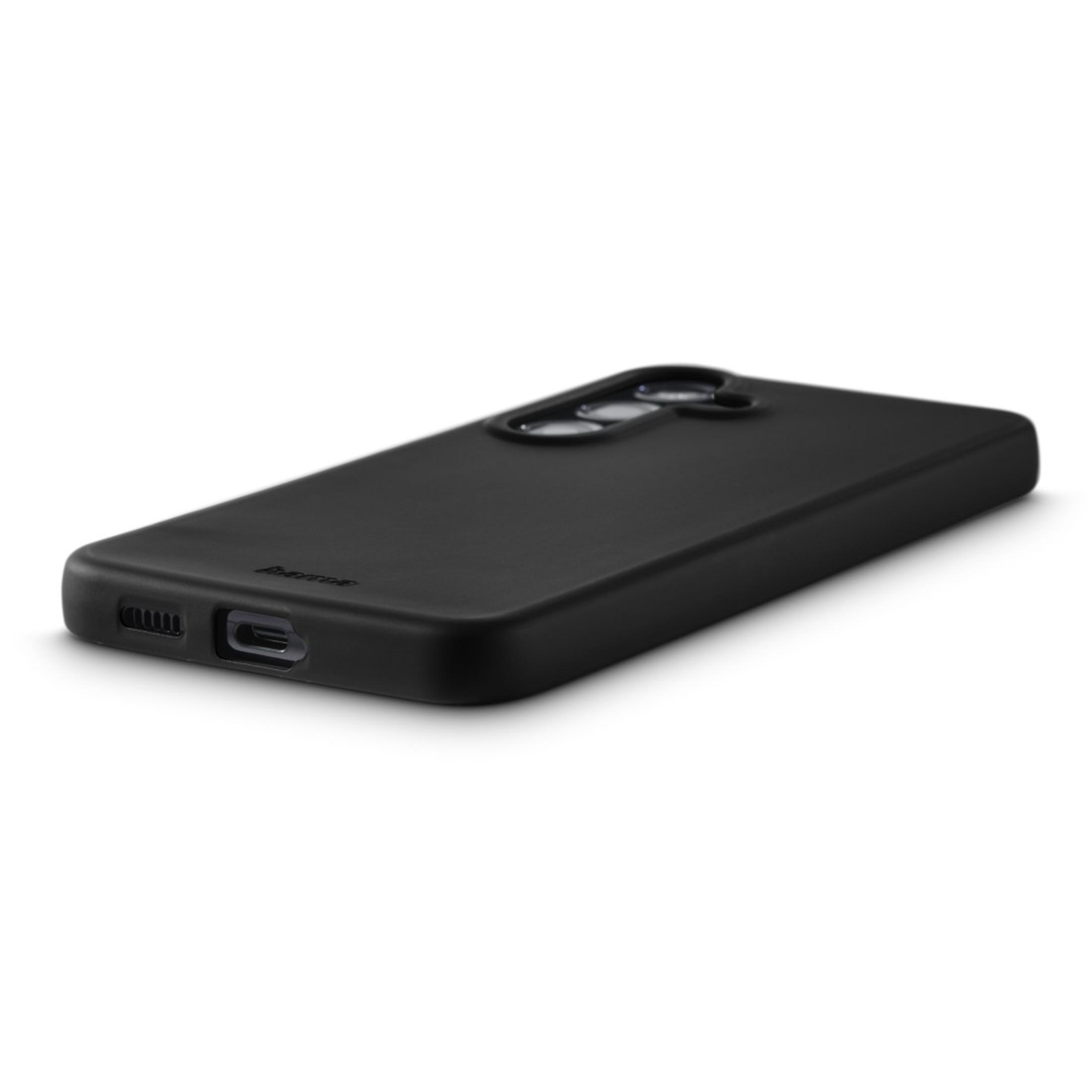 Coque de téléphone noire sur une surface blanche. La coque montre son dos, avec des découpes pour la caméra.
