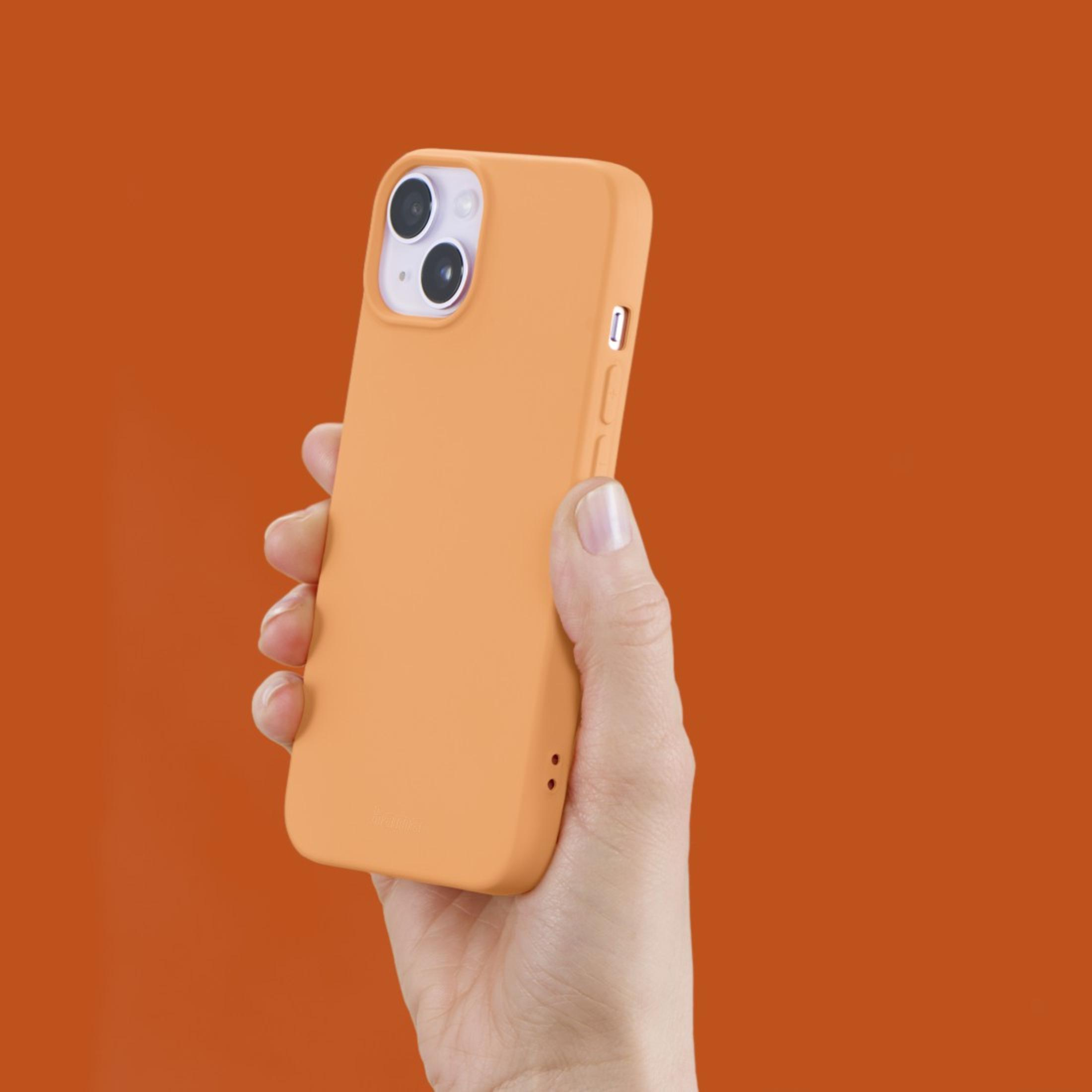 Main tenant une coque de téléphone orange. Fond orange.