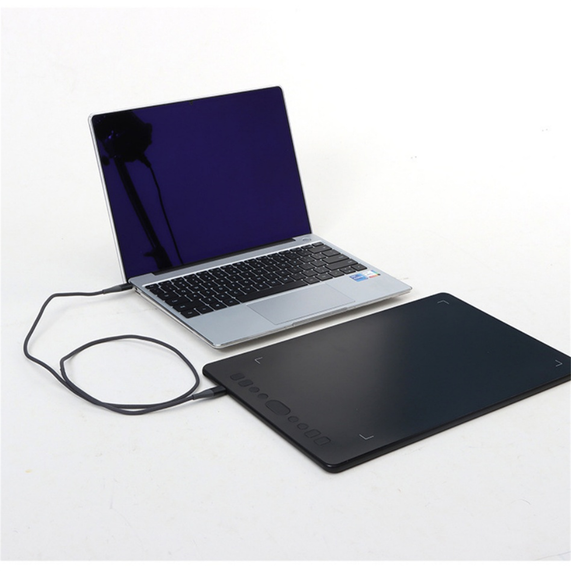 Laptop verbunden mit schwarzem Zeichentablett. Beide auf weißem Untergrund.