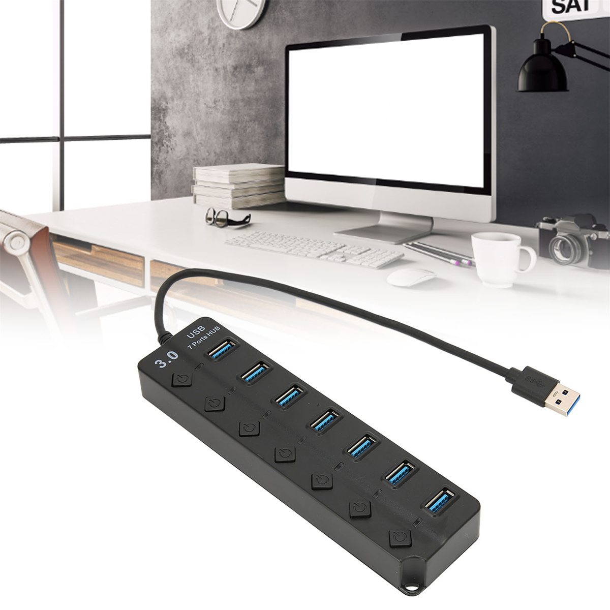 Ein schwarzer USB-Hub steht auf einem Schreibtisch in der Nähe eines Monitors und anderer Gegenstände.