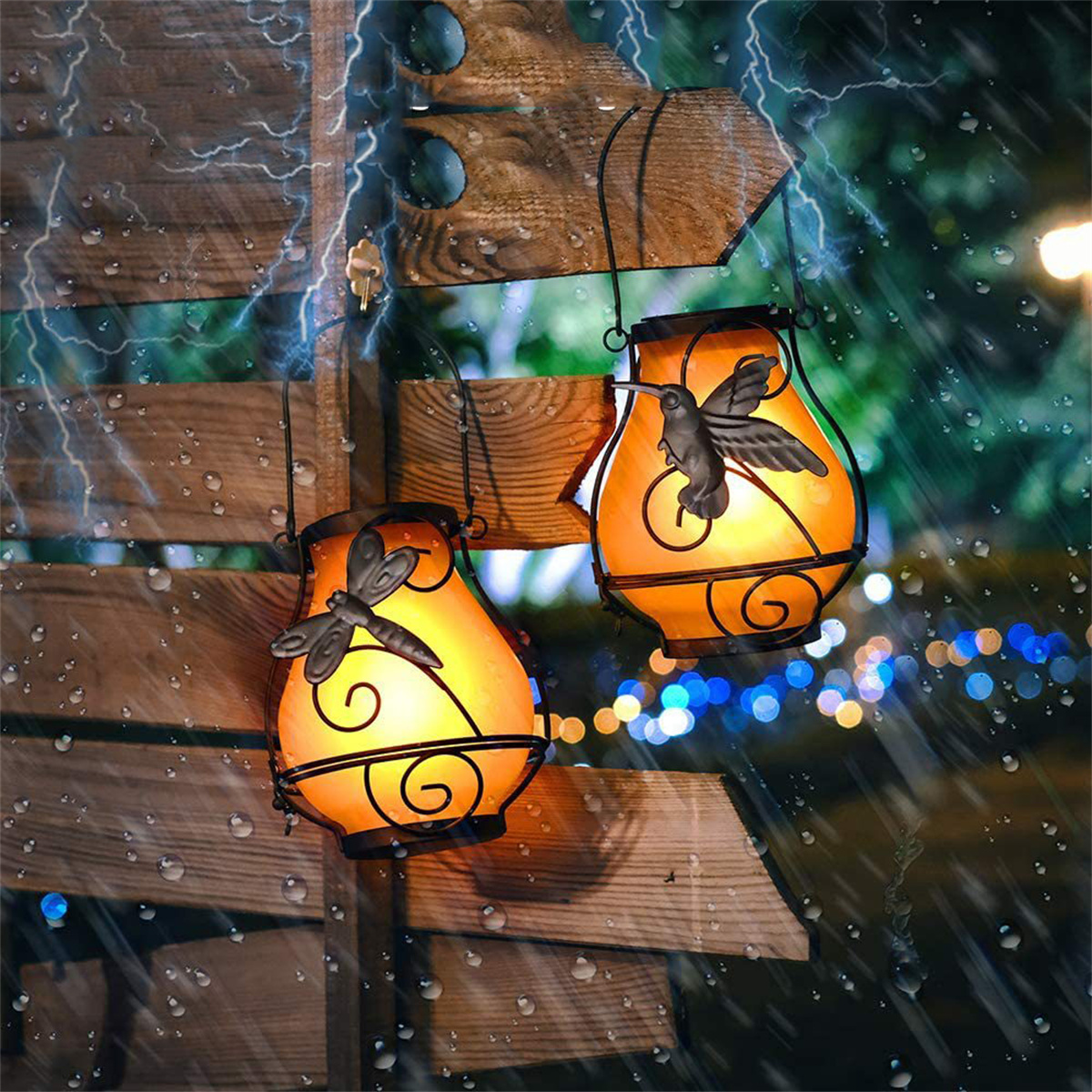 Zwei laternenförmige Lichter an einem Holzschild. Eines hat eine Libelle, das andere einen Kolibri.