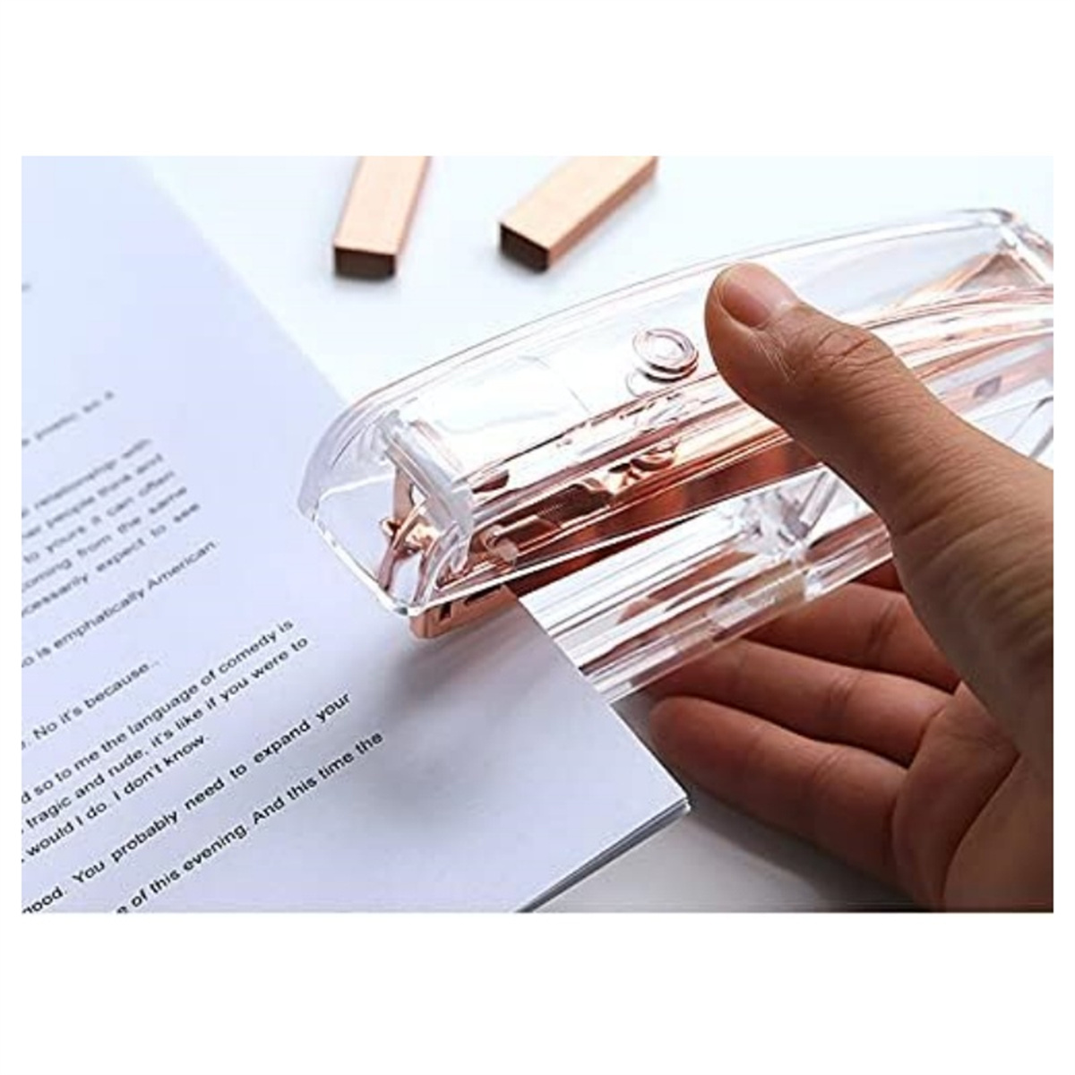 Eine Hand heftet Papiere mit einem transparenten Hefter. Zwei goldene Heftklammern sind ebenfalls zu sehen.