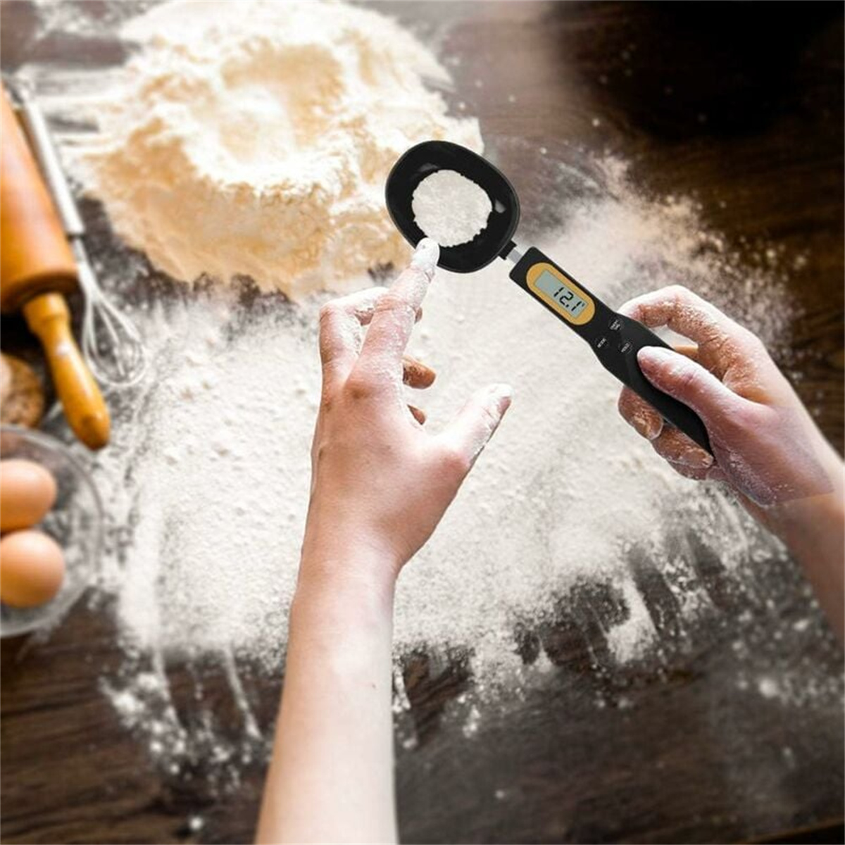 Person misst Mehl mit einer digitalen Löffelwaage auf einem Holztisch.