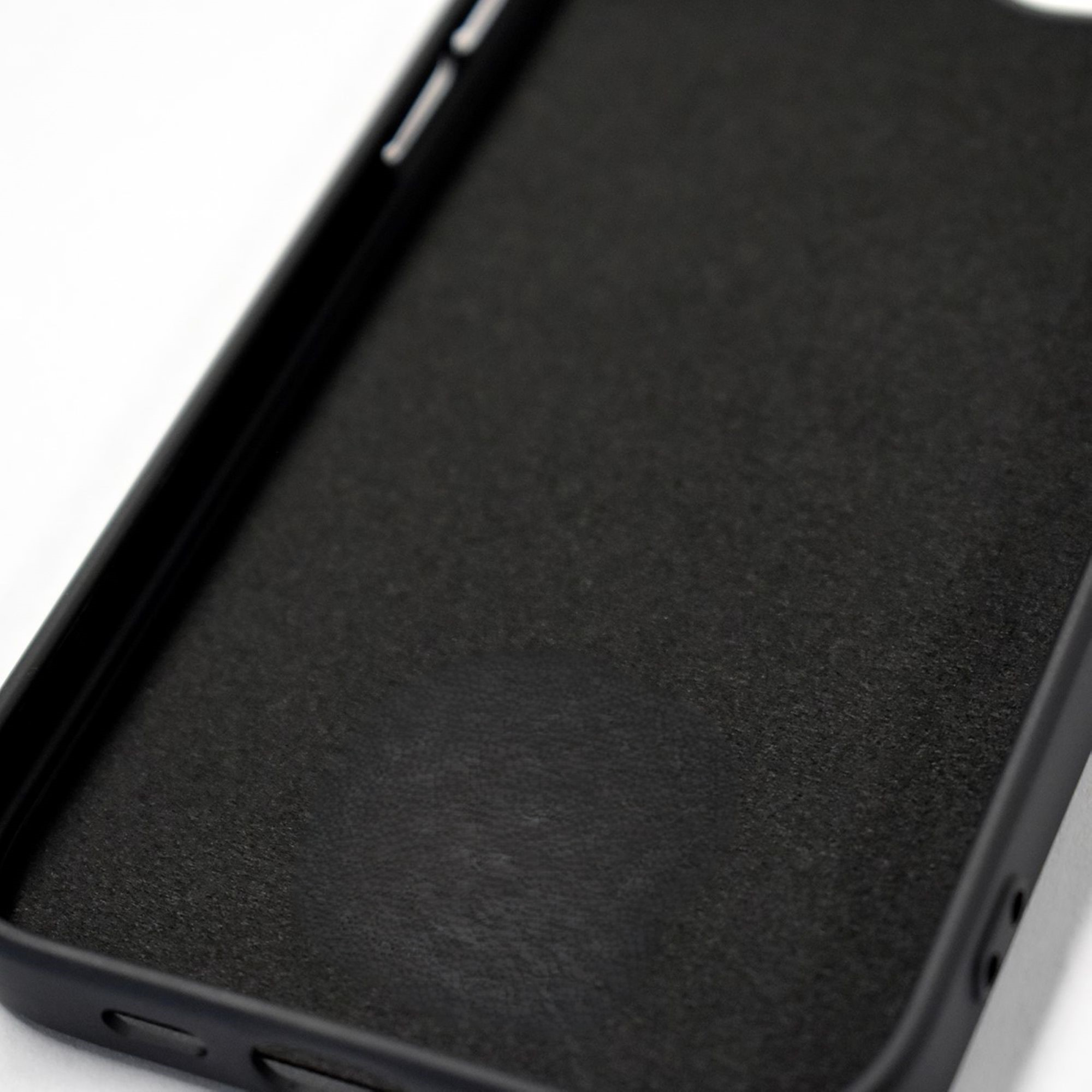Coque de téléphone noire avec une texture semblable au cuir. Montre l'intérieur de la coque.