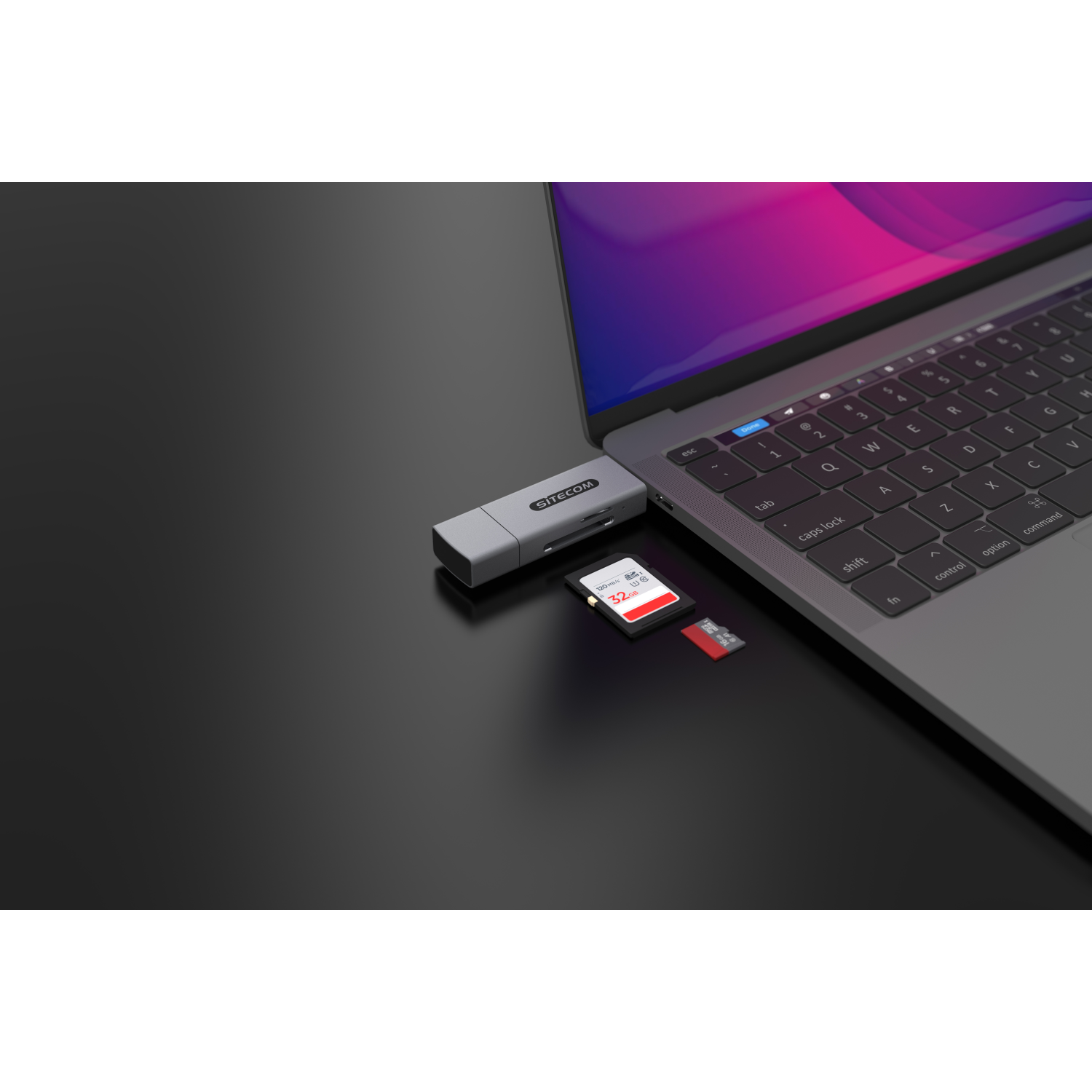 Un laptop con un lettore di schede SD e un'unità USB collegati. C'è una scheda SD rossa inserita.