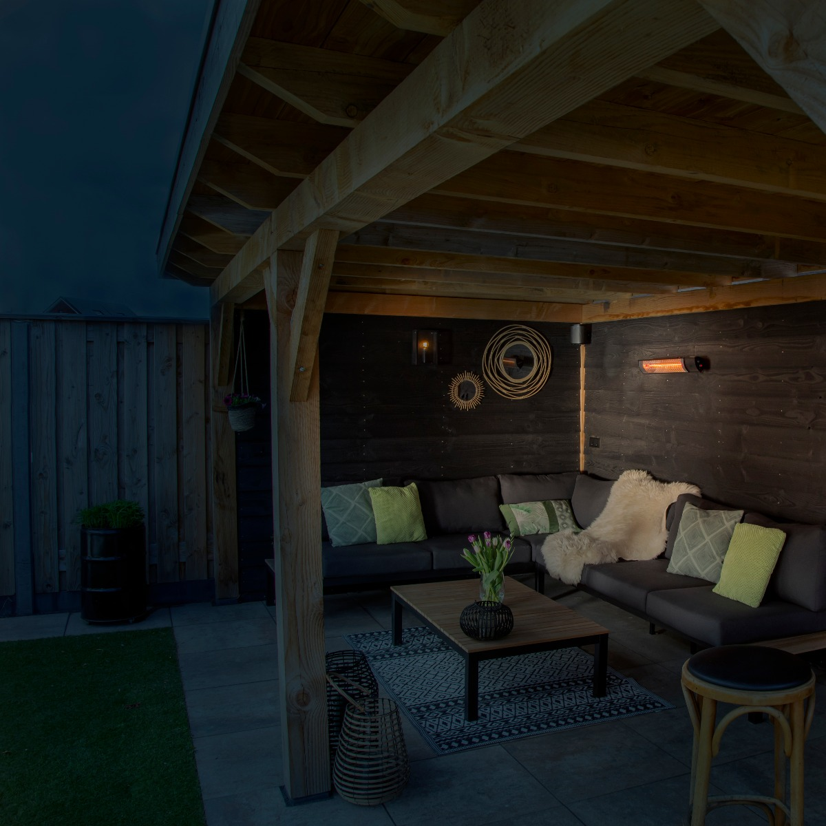 An outdoor patio area at dusk with seating, lighting, and a wooden structure.