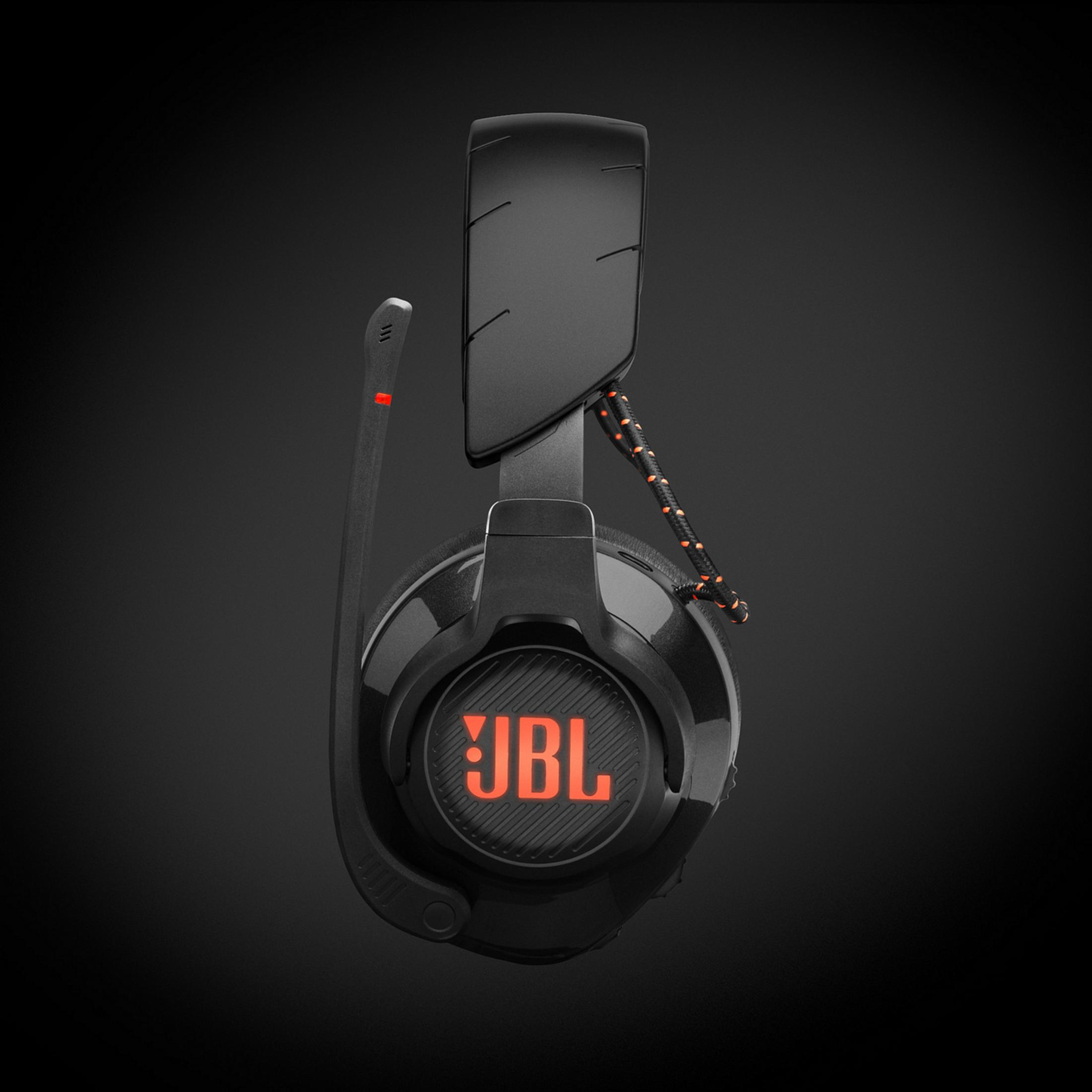 Czarne słuchawki JBL z pomarańczowymi akcentami i mikrofonem. Czarne tło.
