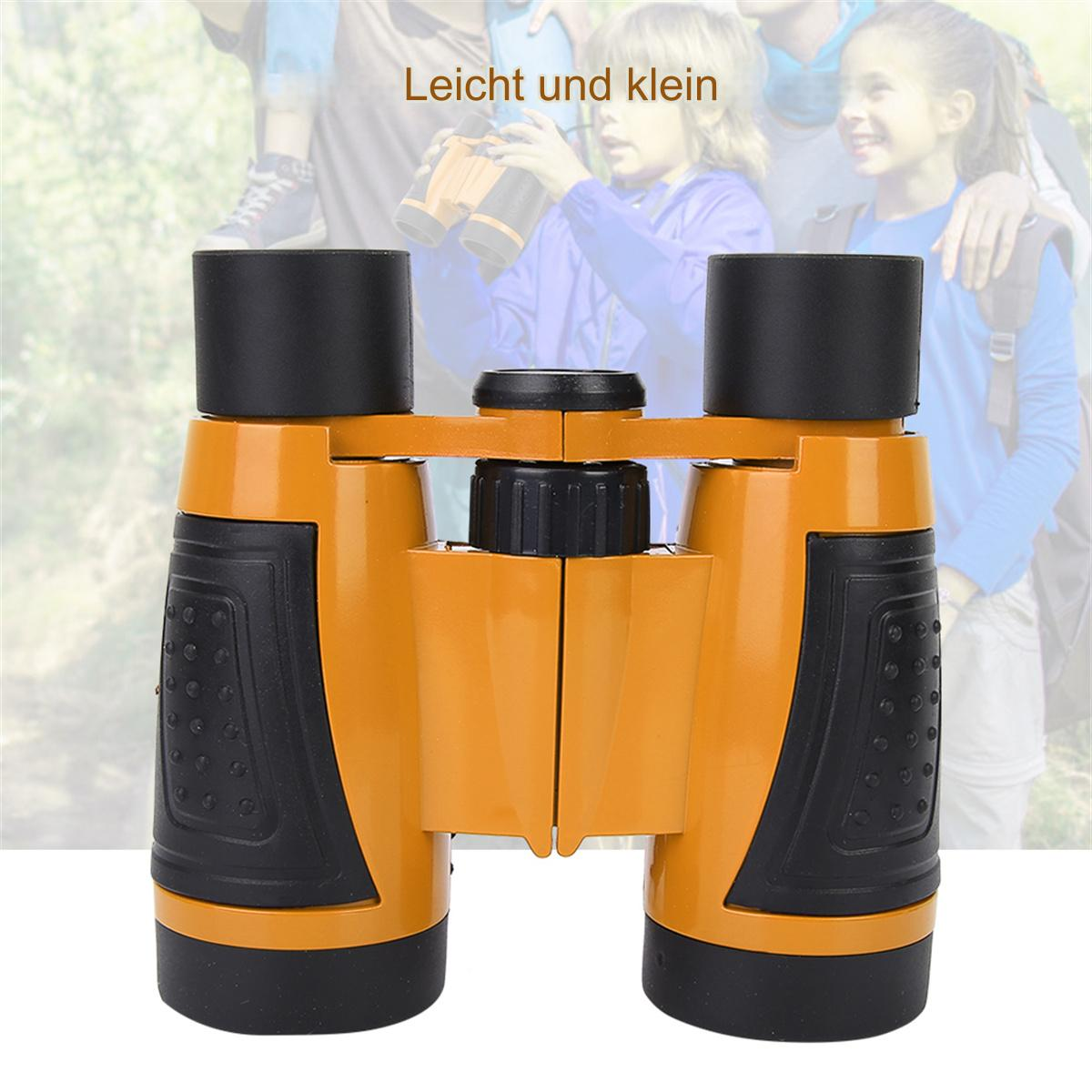 Orange und schwarze Ferngläser, mit zwei verschwommenen Kindern im Hintergrund, die blaue Hemden tragen.