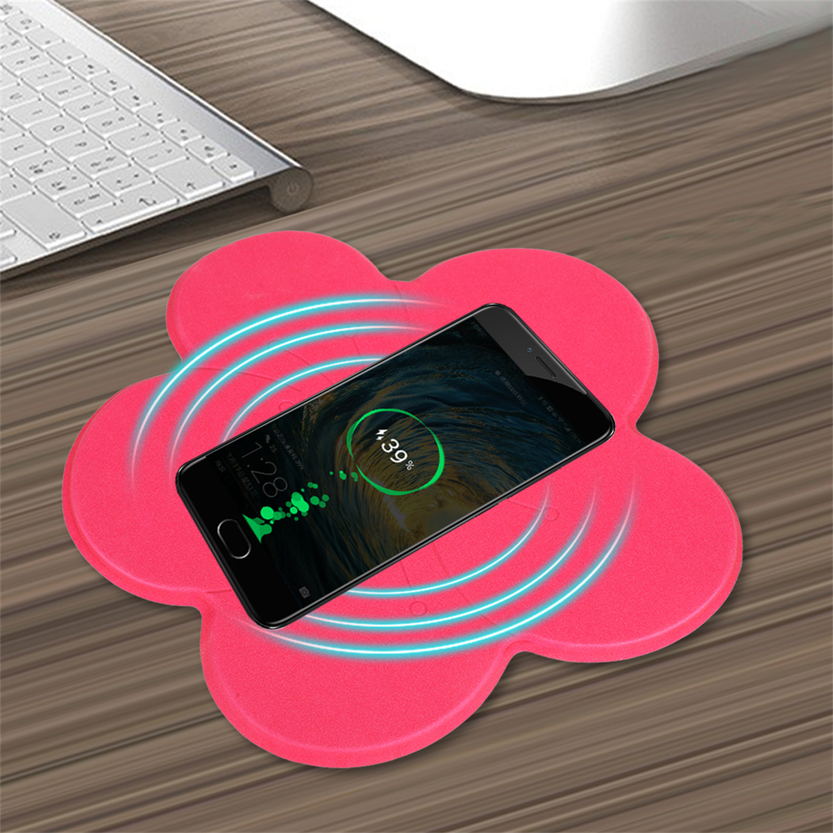 Rosafarbener blütenförmiger kabelloser Ladegerät mit einem schwarzen Telefon darauf. Ladesymbol.
