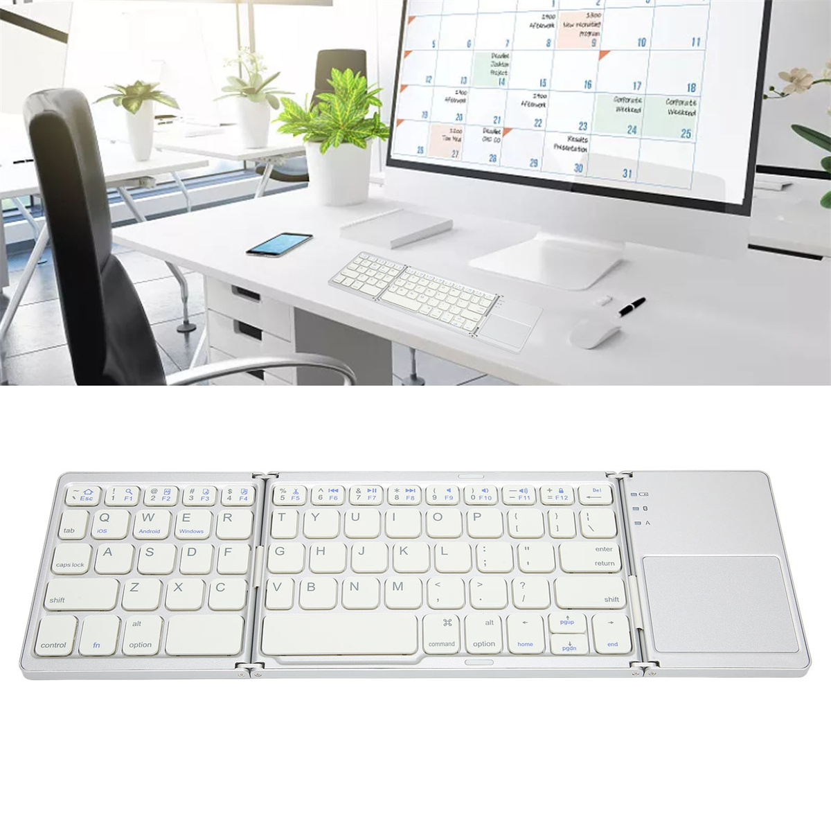 Faltbare Tastatur und Tablet auf weißem Schreibtisch, mit Monitor im Hintergrund.