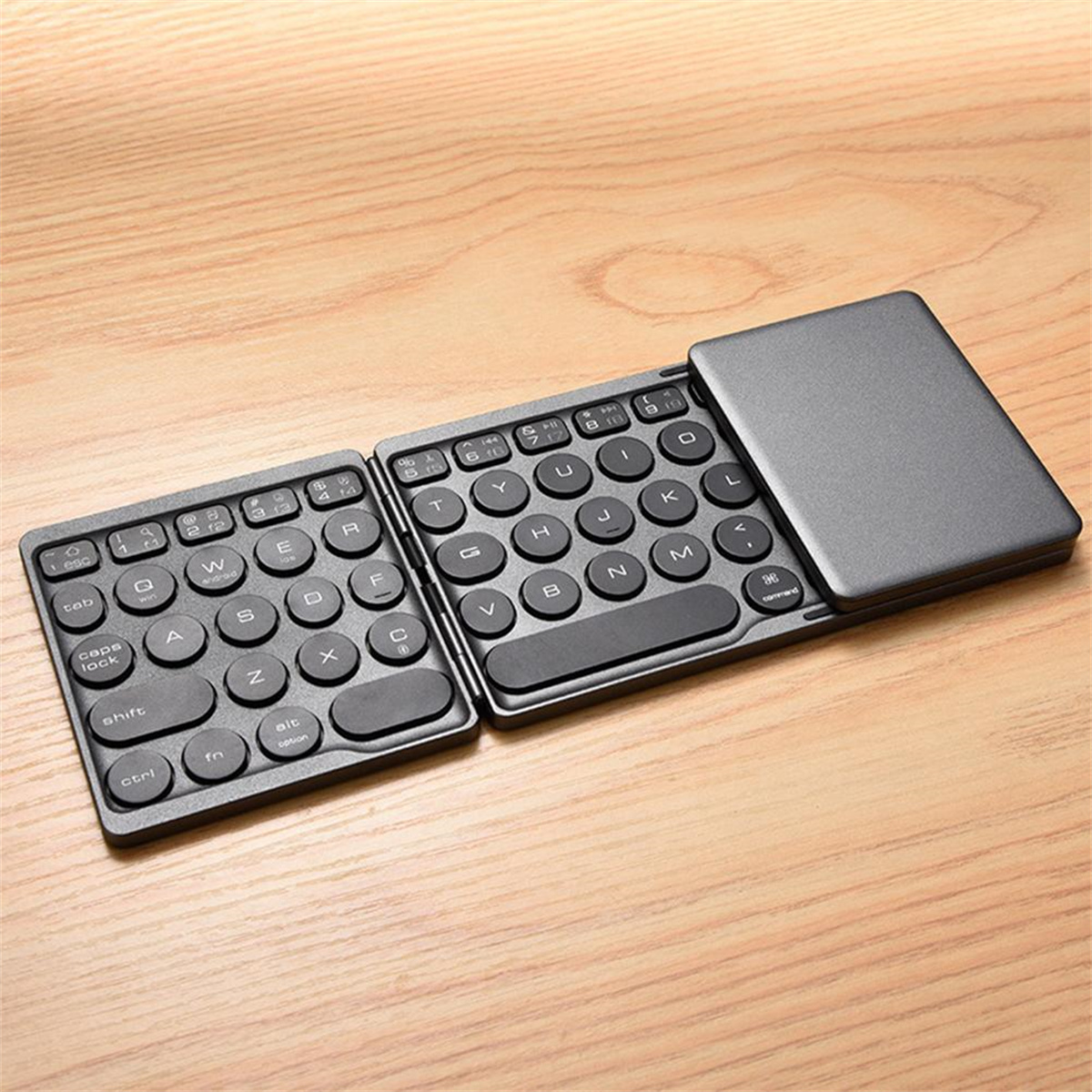 Faltbare Tastatur mit geöffneten und geschlossenen Teilen. Schwarze Tasten auf Holztisch.