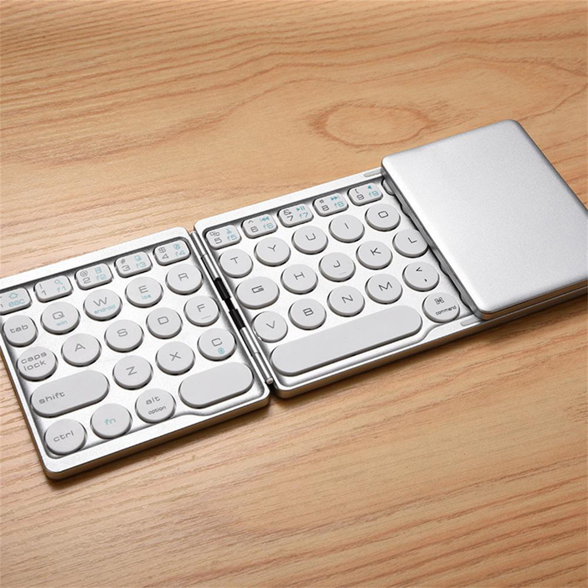Silberne, faltbare Tastatur auf Holzoberfläche, Tasten sind weiß.