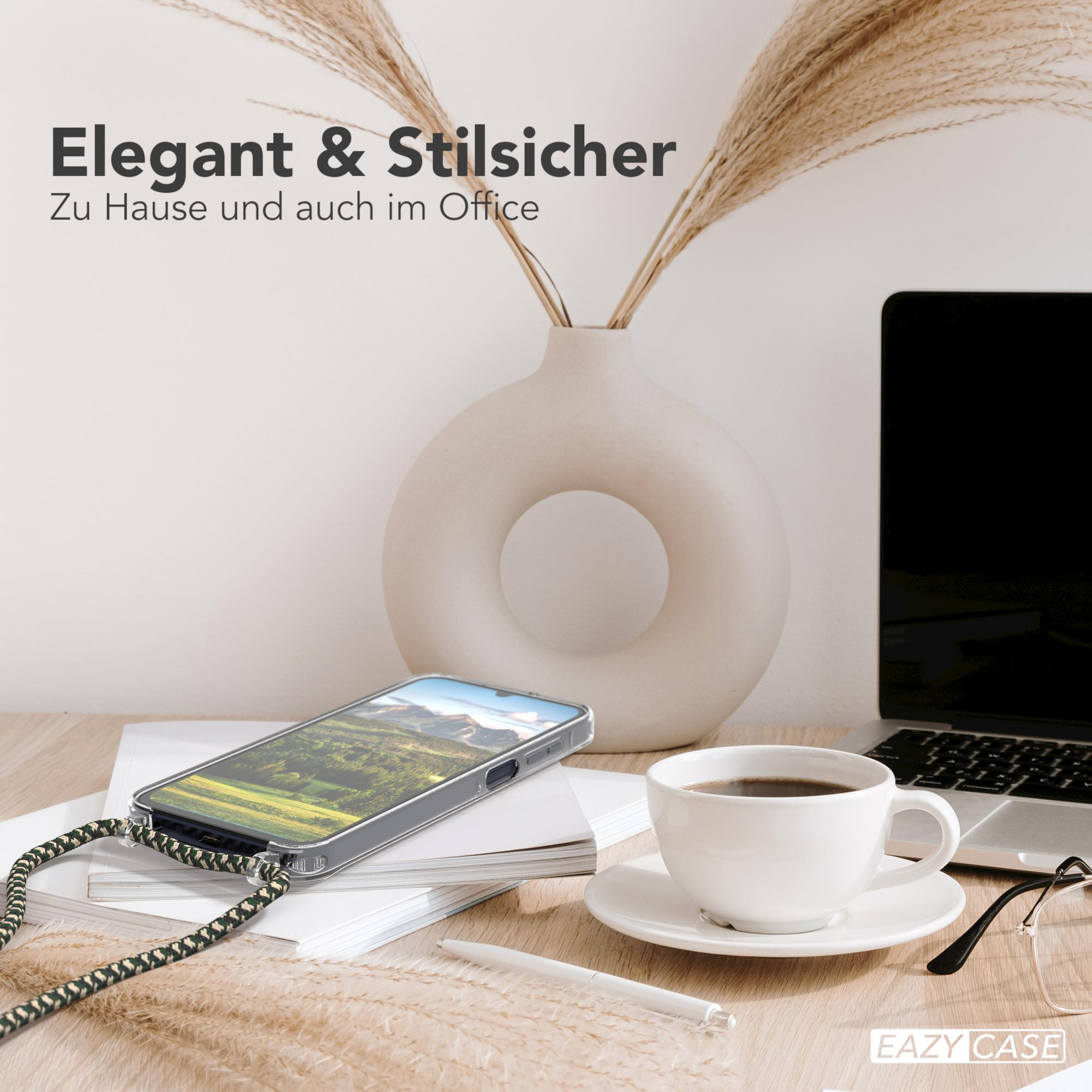 Telefon mit Hülle und Band auf dem Schreibtisch, mit Kaffeetasse, Pflanze und Laptop im Hintergrund.