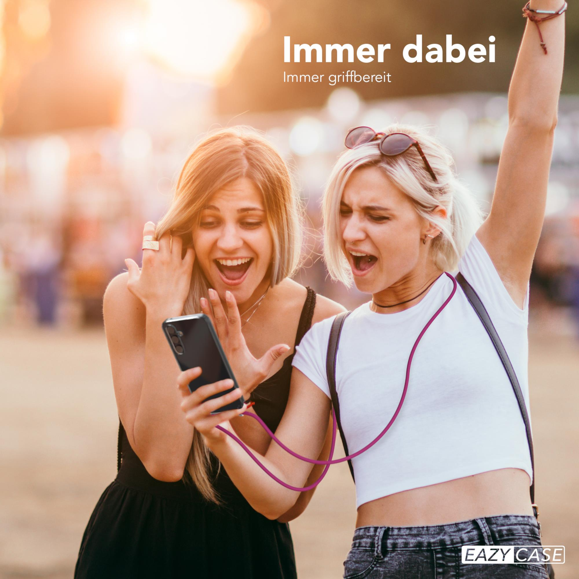 Zwei Frauen schauen auf ein Telefon. Eine hält das Telefon mit einem lila Kabel. Sie lächeln.