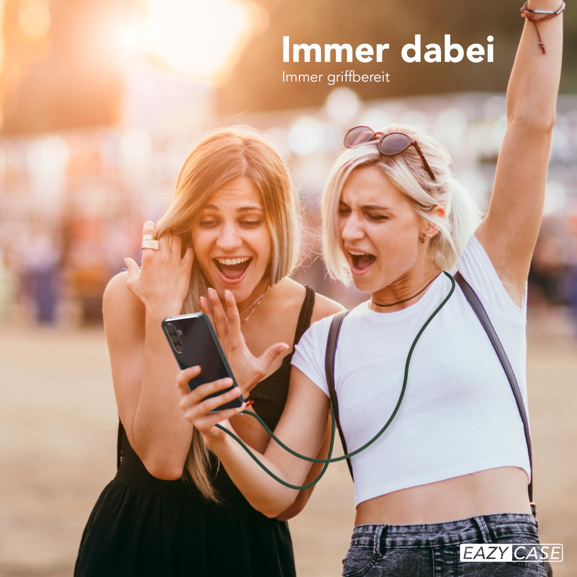 Zwei Frauen schauen auf ein Handy. Eine hält es, die andere hebt den Arm.