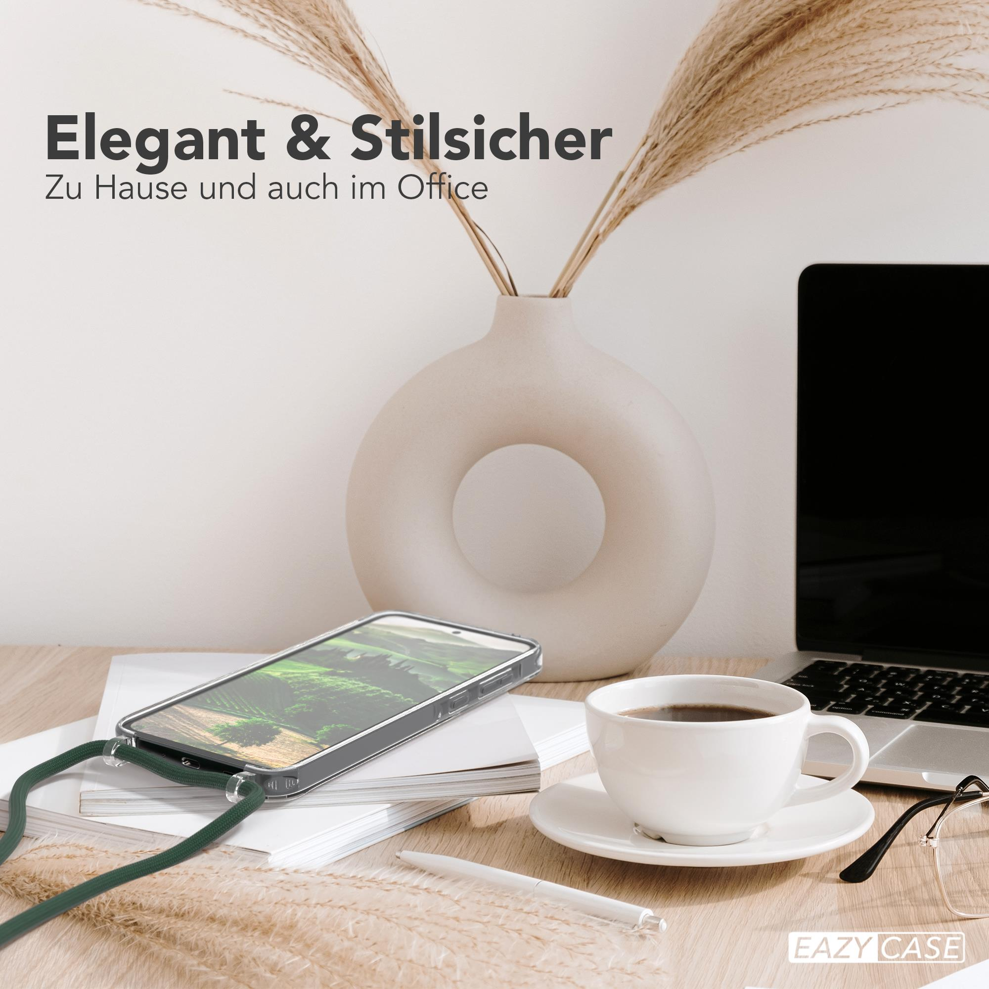 Ein Schreibtisch mit Handyhülle, Kaffeetasse und Laptop. Vase und Pflanzen im Hintergrund.