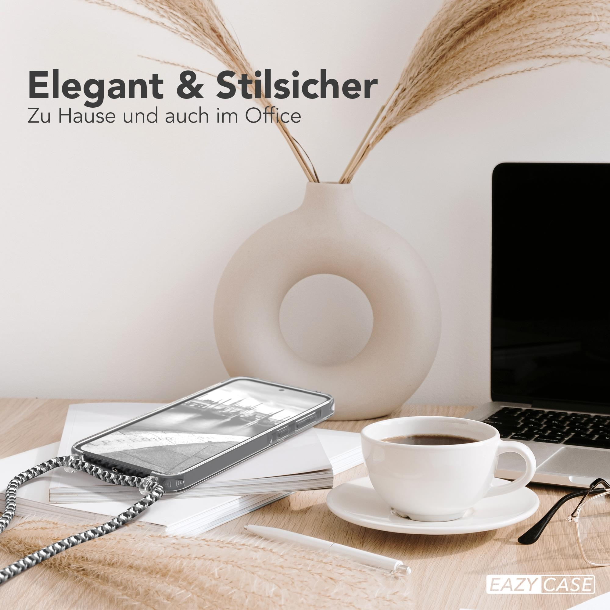 Telefon in Hülle mit schwarz-silbernem Lanyard auf Schreibtisch mit Kaffee und Laptop.