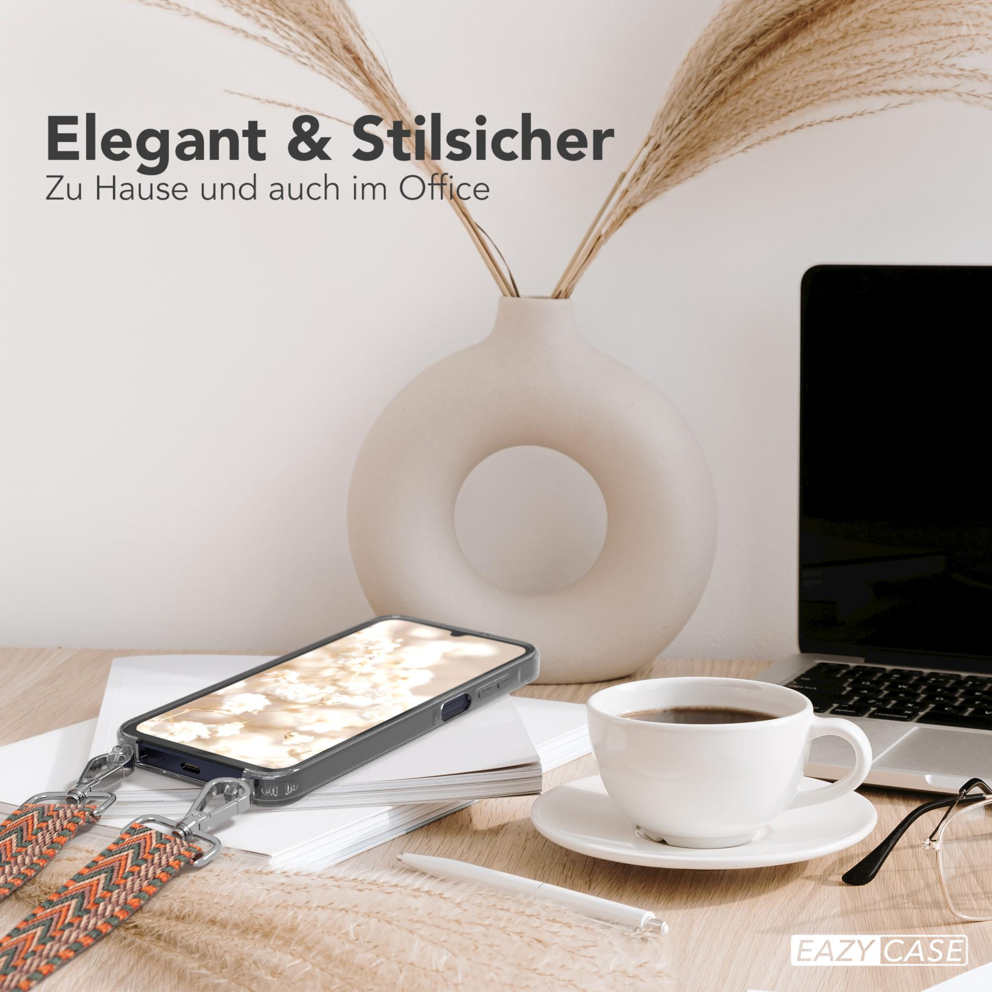 Ein Telefon mit Trageband auf einem Schreibtisch. Eine Vase mit Pflanzen und Laptop.